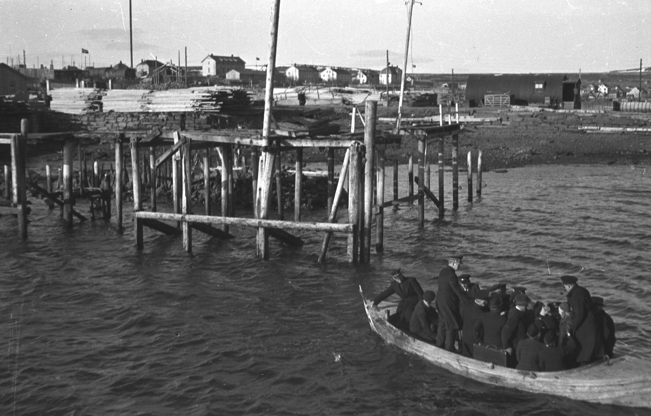 Foto: Gammelt svart-hvitt-bilde av en rekke menn i uniform fra Frelsesarmeen som ankommer en kai i en liten båt.