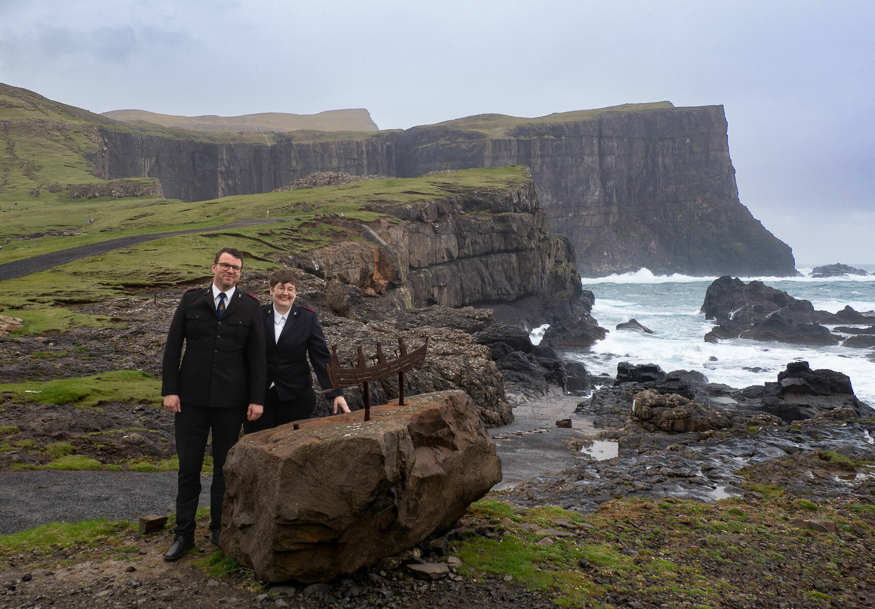 Ektepar i svarte uniformer fra Frelsesarmeen. Rundt dem bar natur og vilt hav.