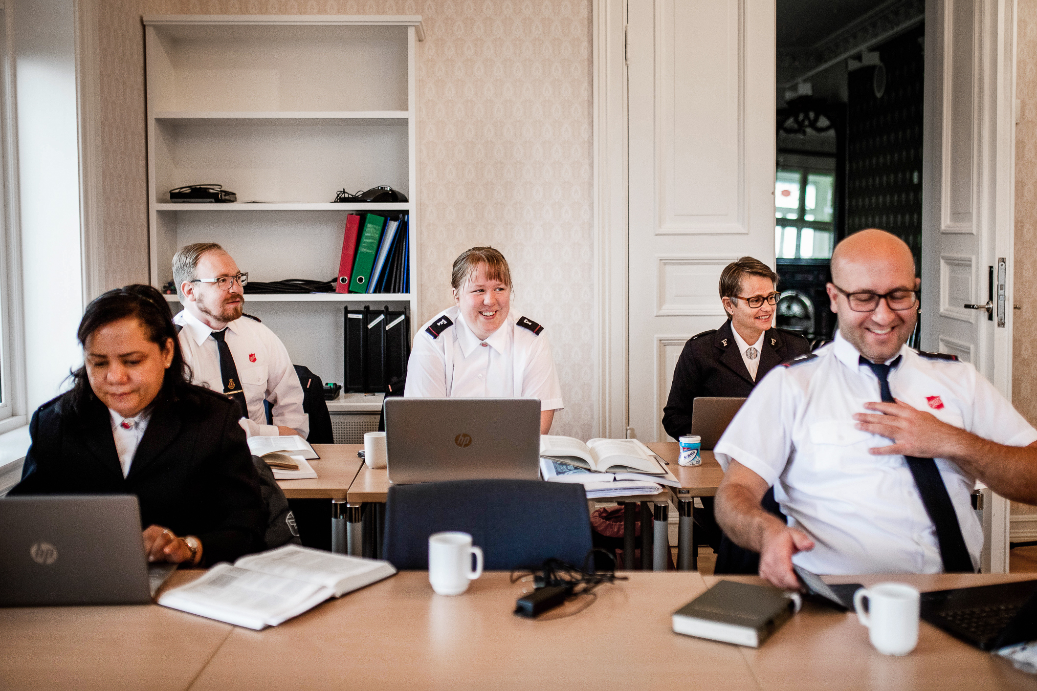 Fem fremtidige frelsesoffiserer i uniform sitter i et klasserom.