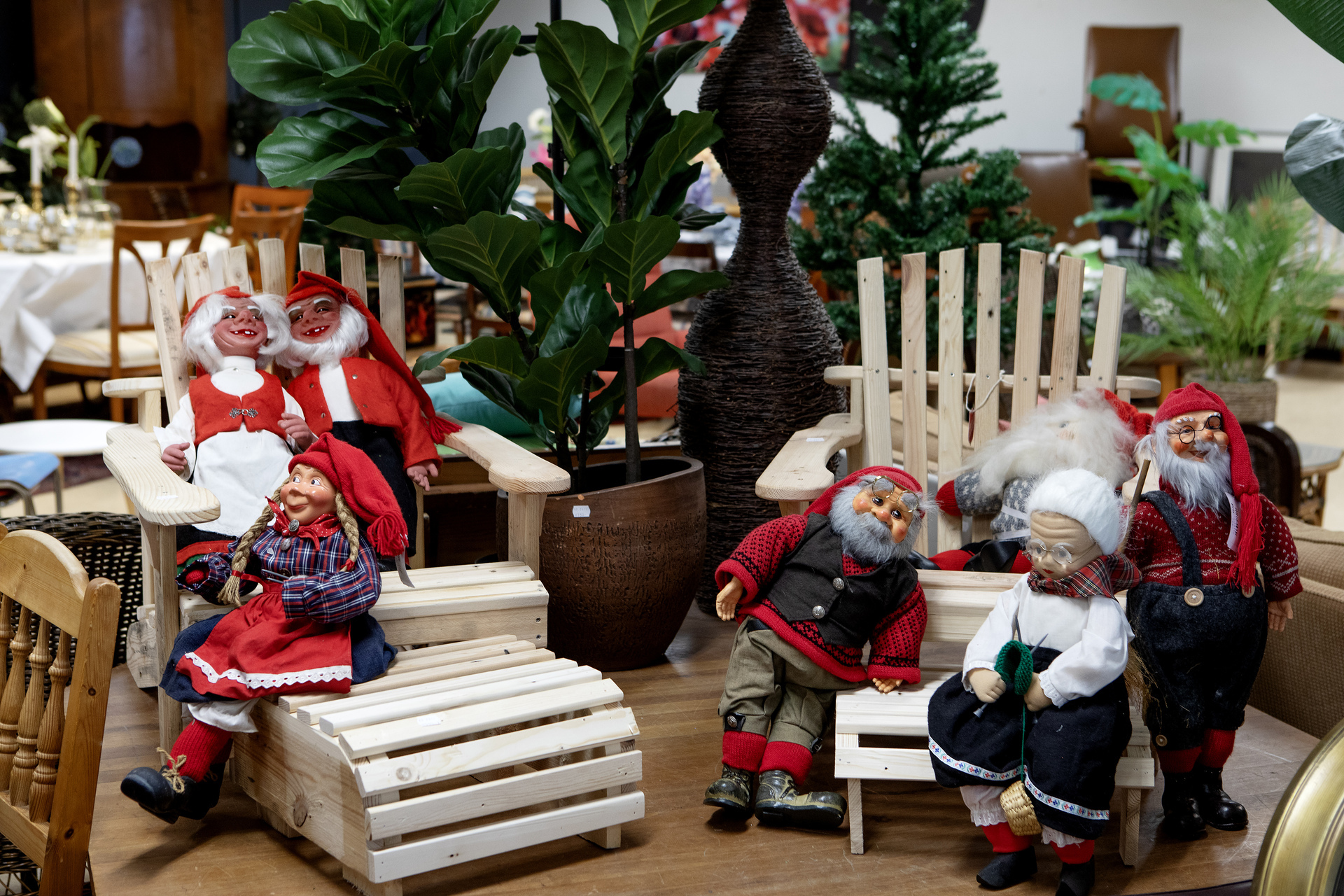 Ulike julenissefigurer er dandert i en butikkutstilling. Nissene sitter på små tremøbler