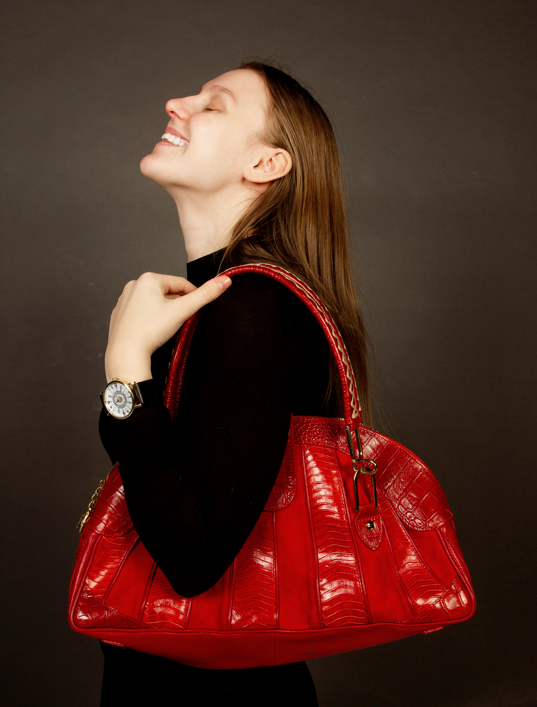 Jente i sort genser holder en knall rød skulderveske