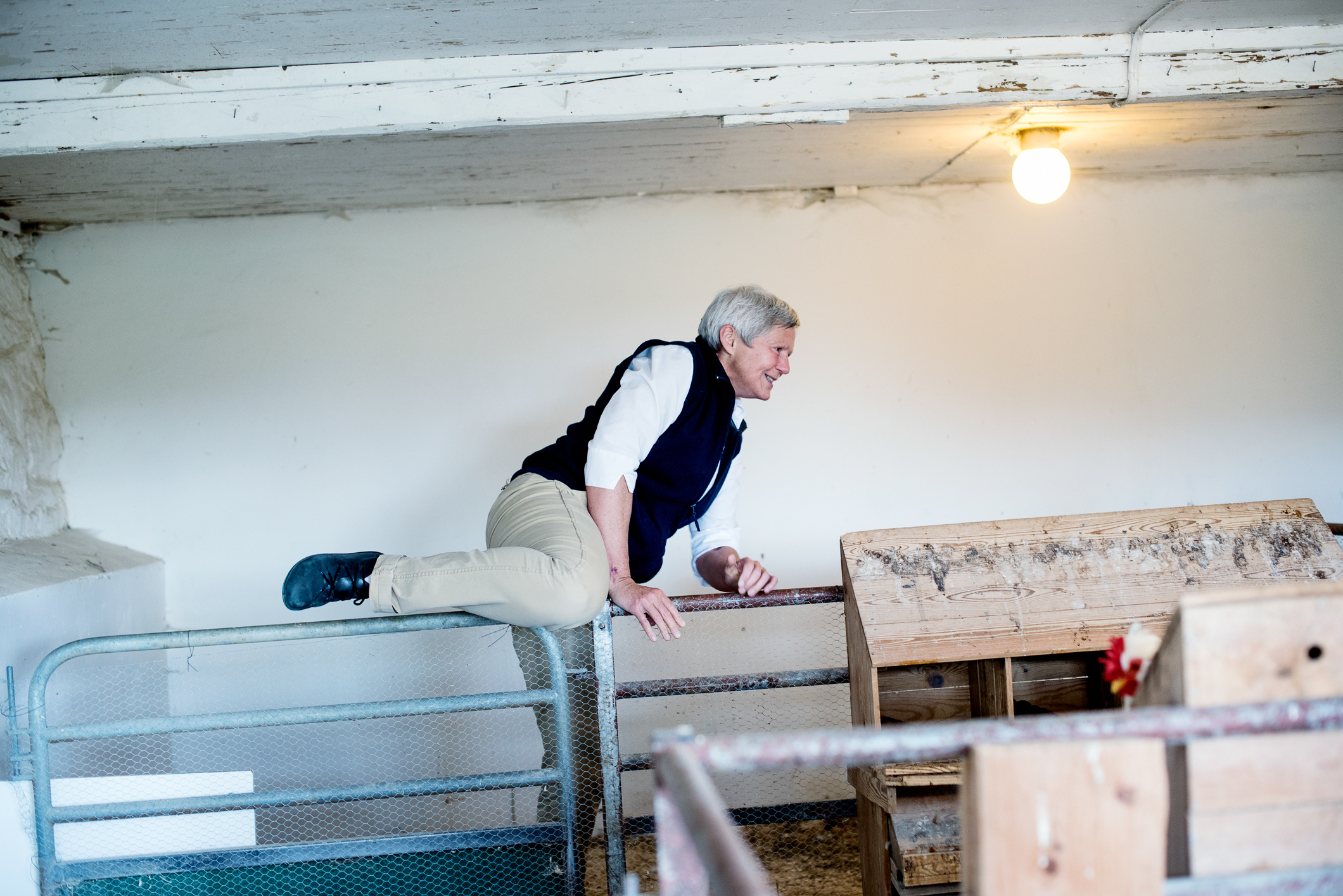 Kvinne som går over en grind inne hos hønene.