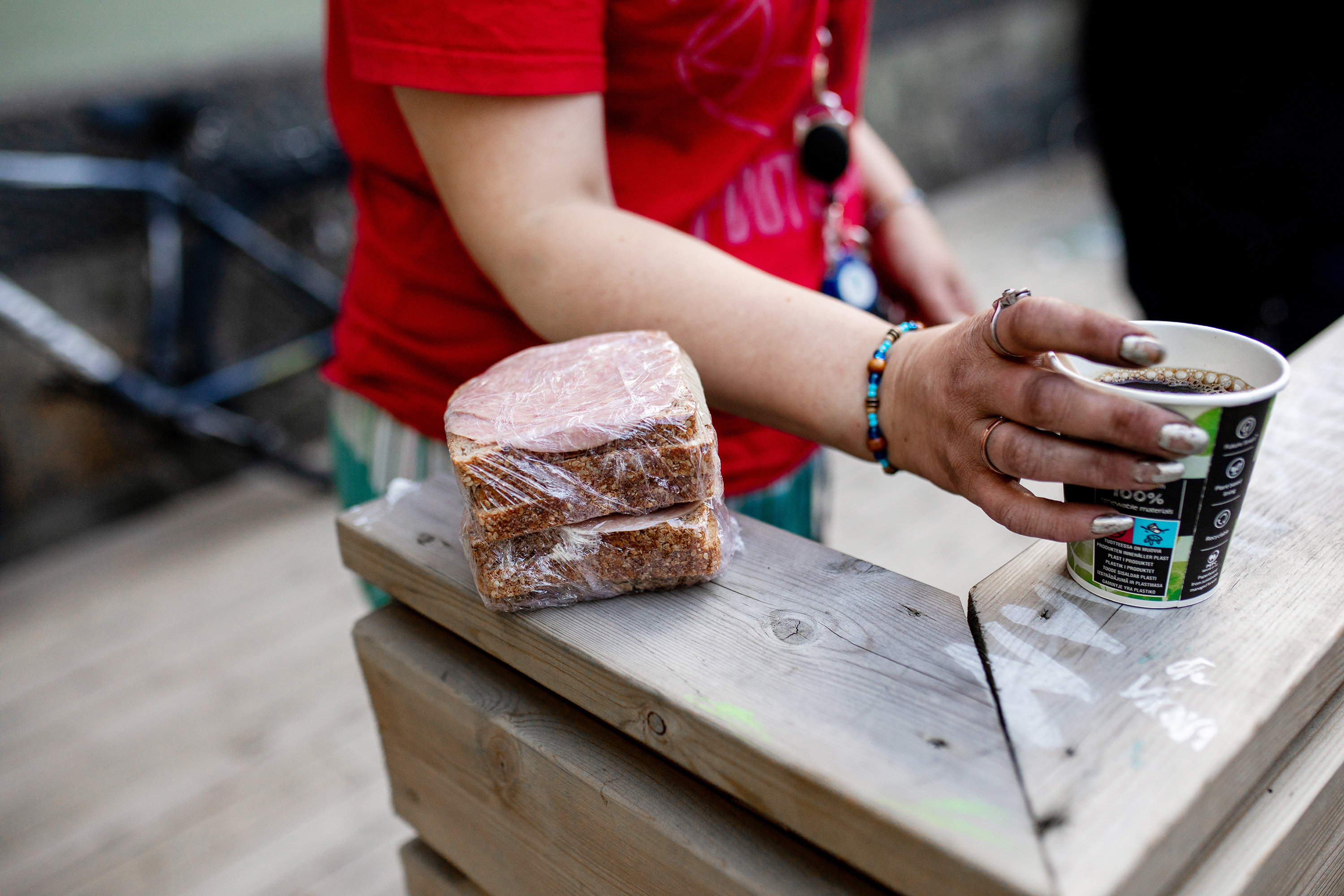 En skitten hånd holder en kopp kaffe og en raus matpakke fra Frelsesarmeens fotpatrulje.