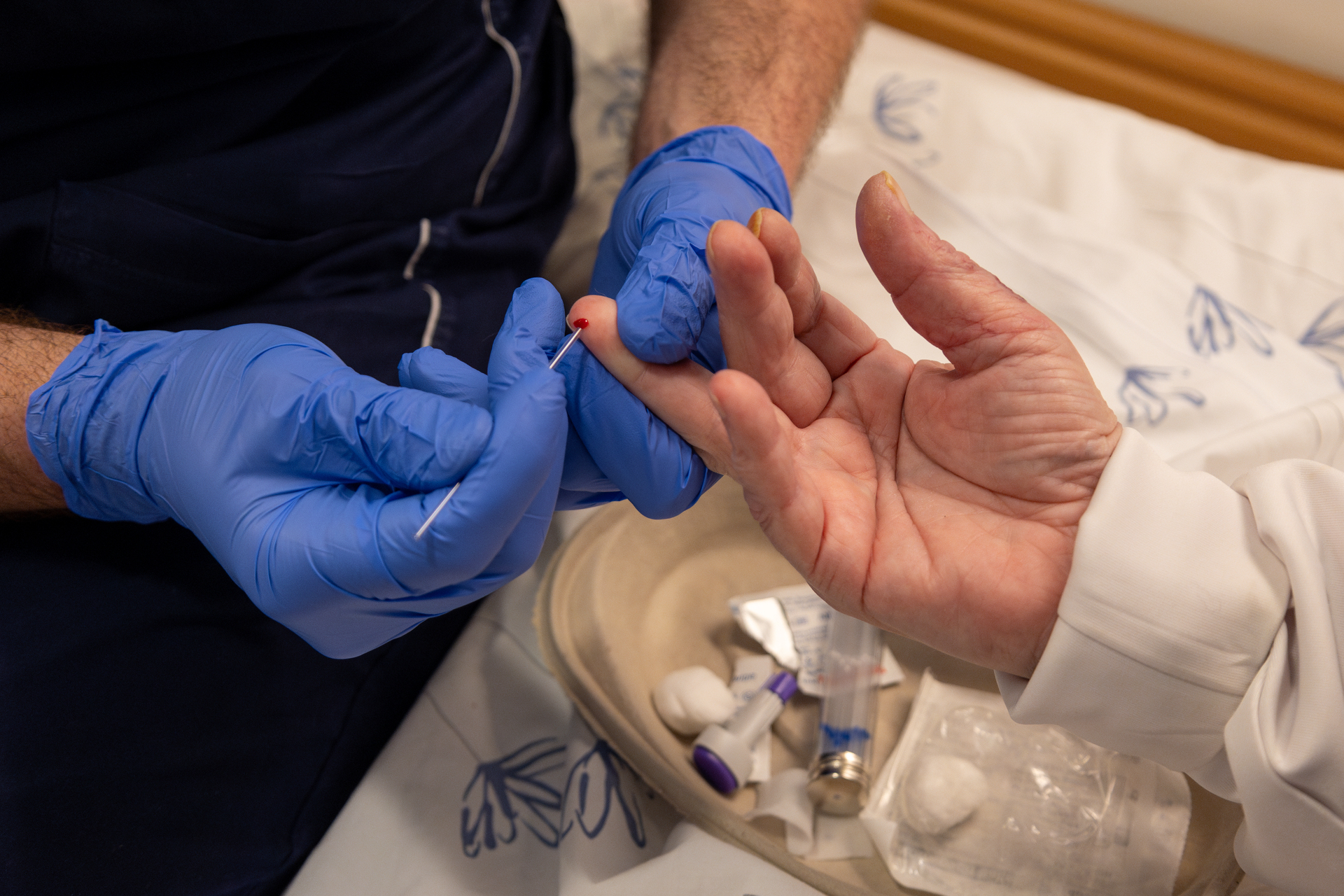 Foto: To bilder etter hverandre, der det første viser armene til en mannlig sykepleier med blå hansker som tar en blodprøve i en finger på en kvinne. Det andre bildet ham sammen med samme pasient som sitter med ryggen til kamera.