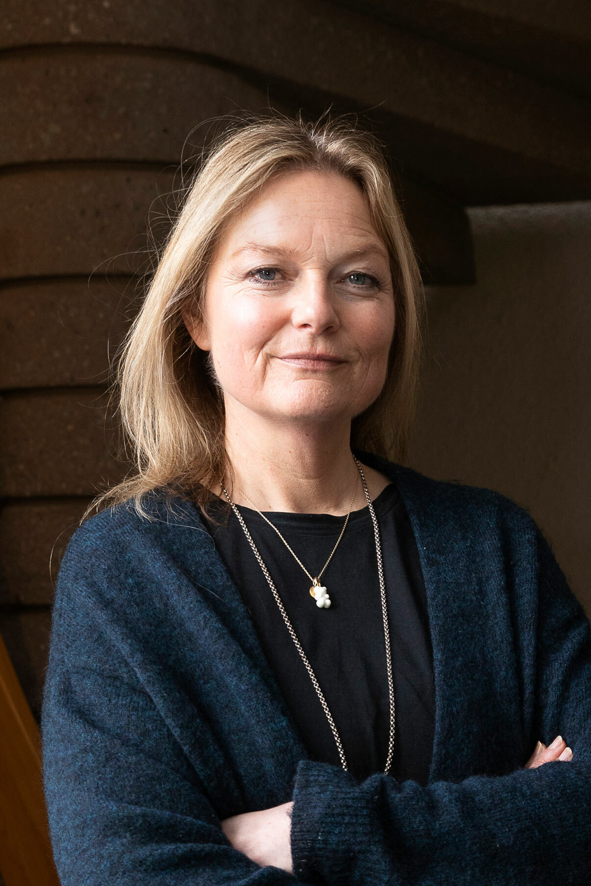 Foto: Kvinne i 50-årene med halvlangt, blondt hår står med armene i kors.