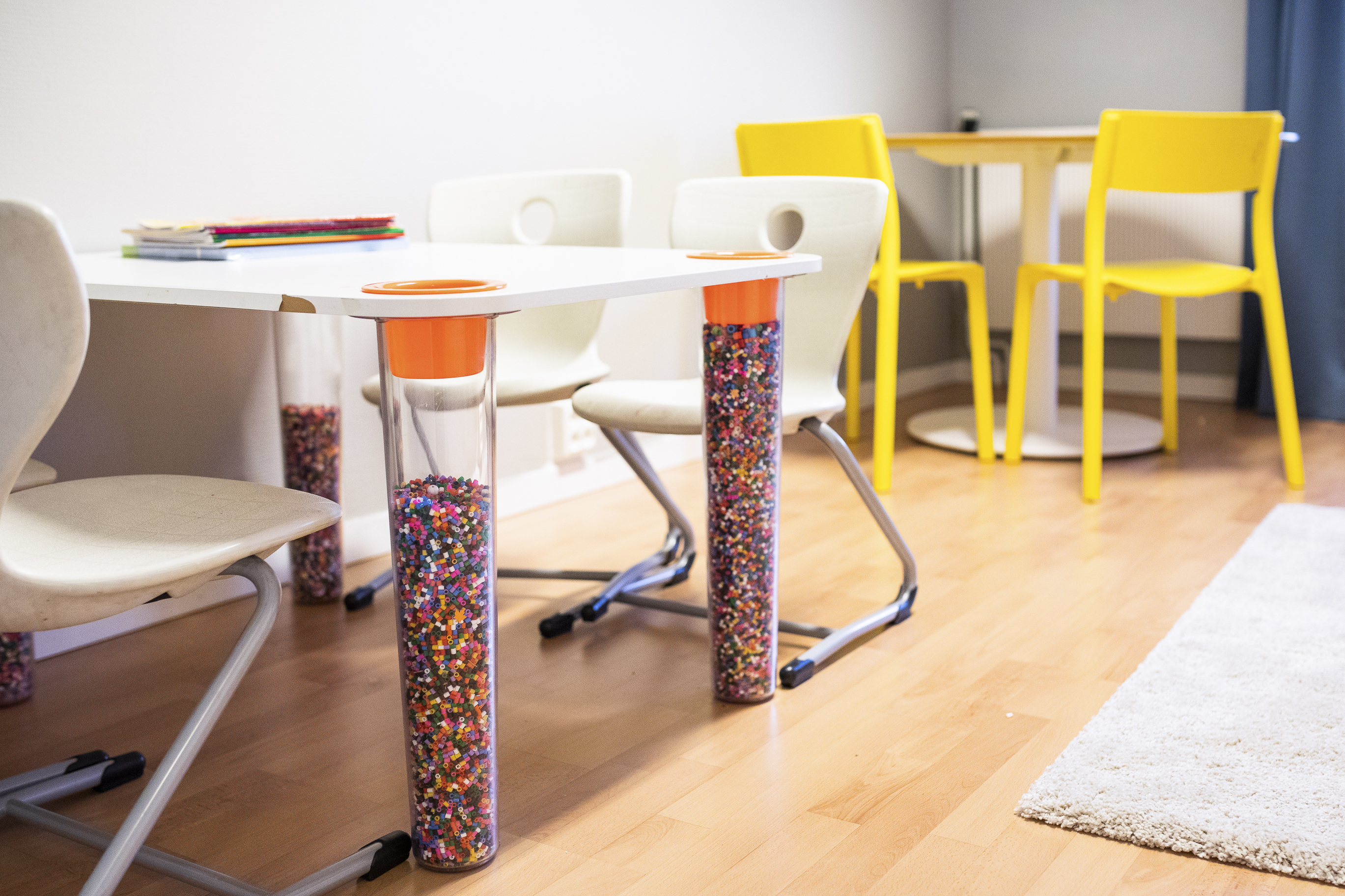 Leke og oppholdsrom med fargerike møbler og bordben fylt av perler