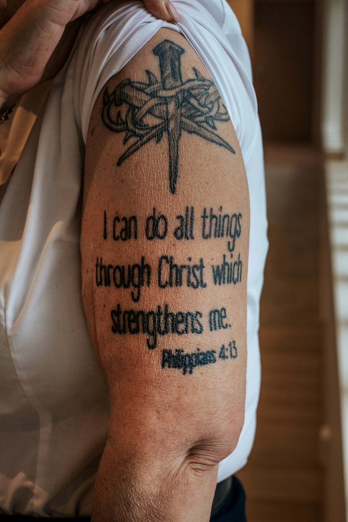 Foto: Nærbilde av arm med blå tatovering. Over teksten er det tegning av et par store spikre viklet inn i torner.