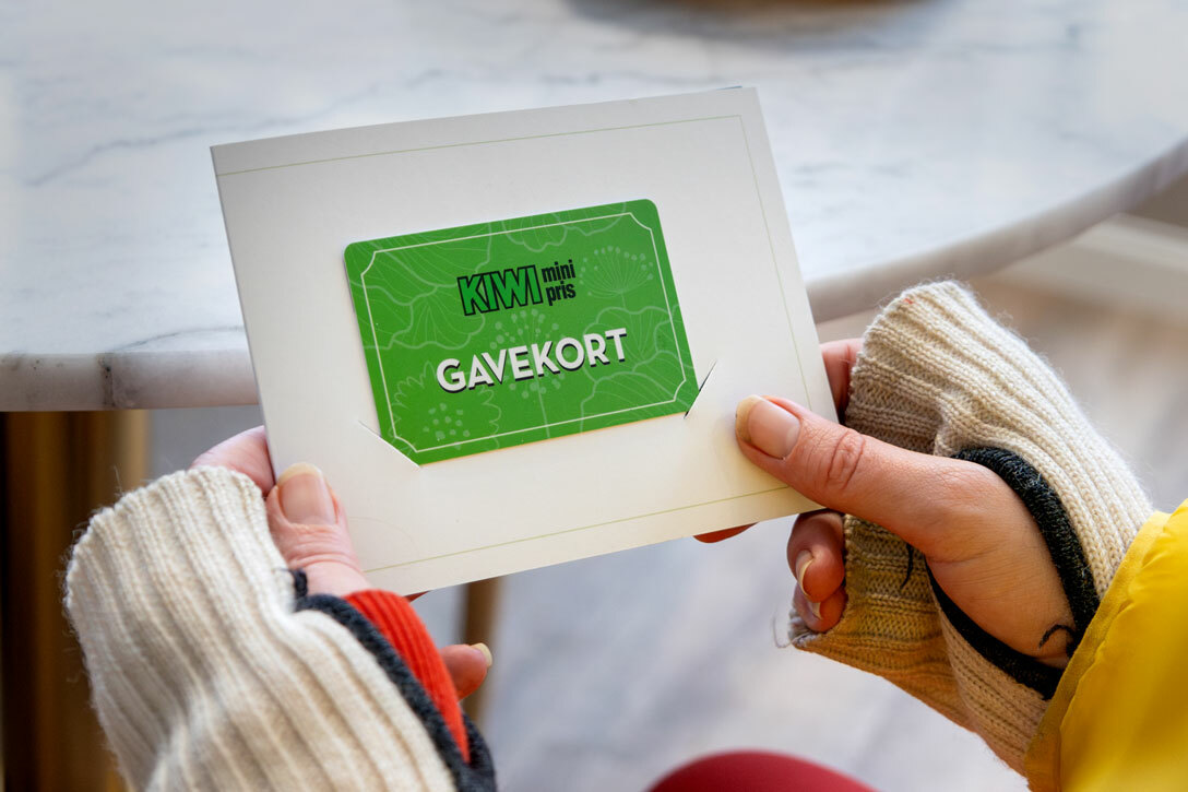 Foto: Kvinnehender holder et grønt gavekort fra Kiwi.