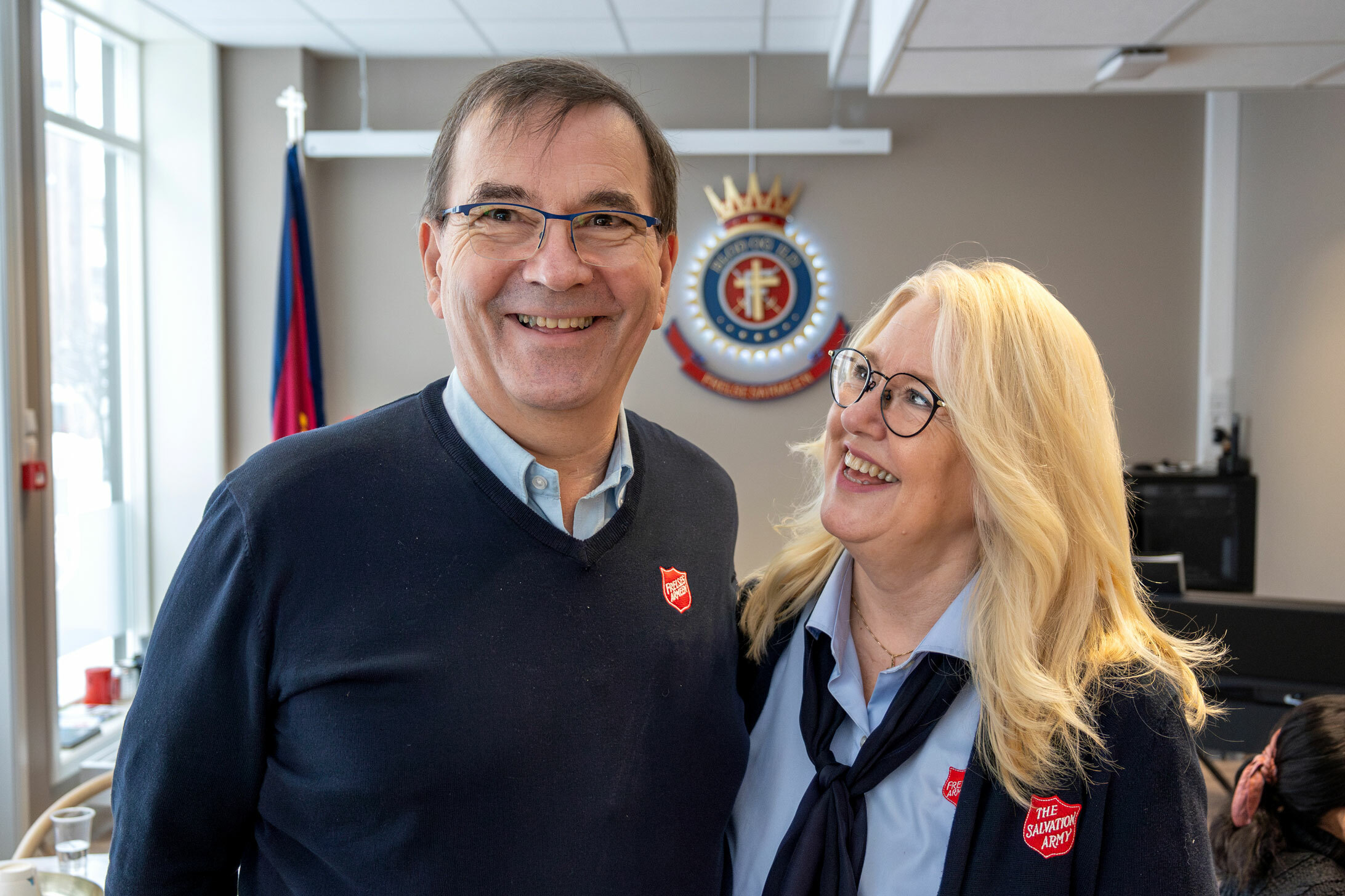 Foto: Kvinne og mann i klær fra Frelsesarmeen. Hun ser opp på ham, han ser i kamera. Han er mørk, hun har halvlangt, blondt hår. Begge har briller.