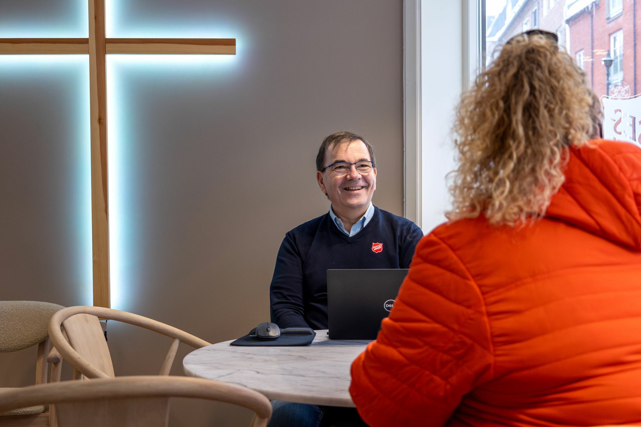 Foto: Mann i 60-årene med mørkt hår og briller sitter ved et bord.