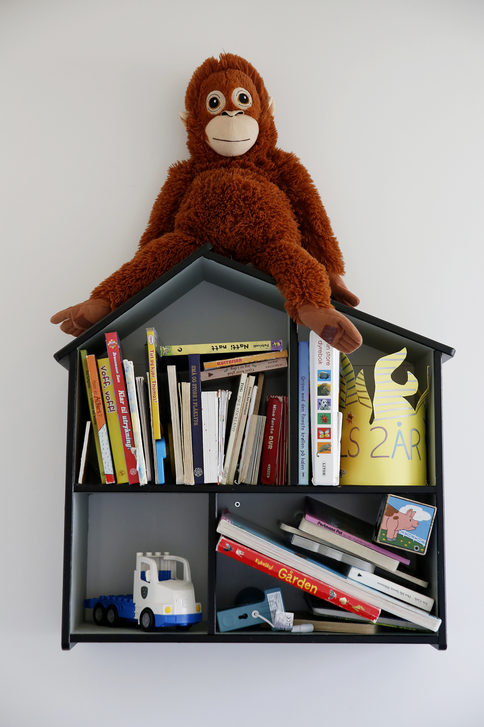 Foto: Bokhylle formet som et hus med barnebøker i og en apekatt som sitter på "taket".
