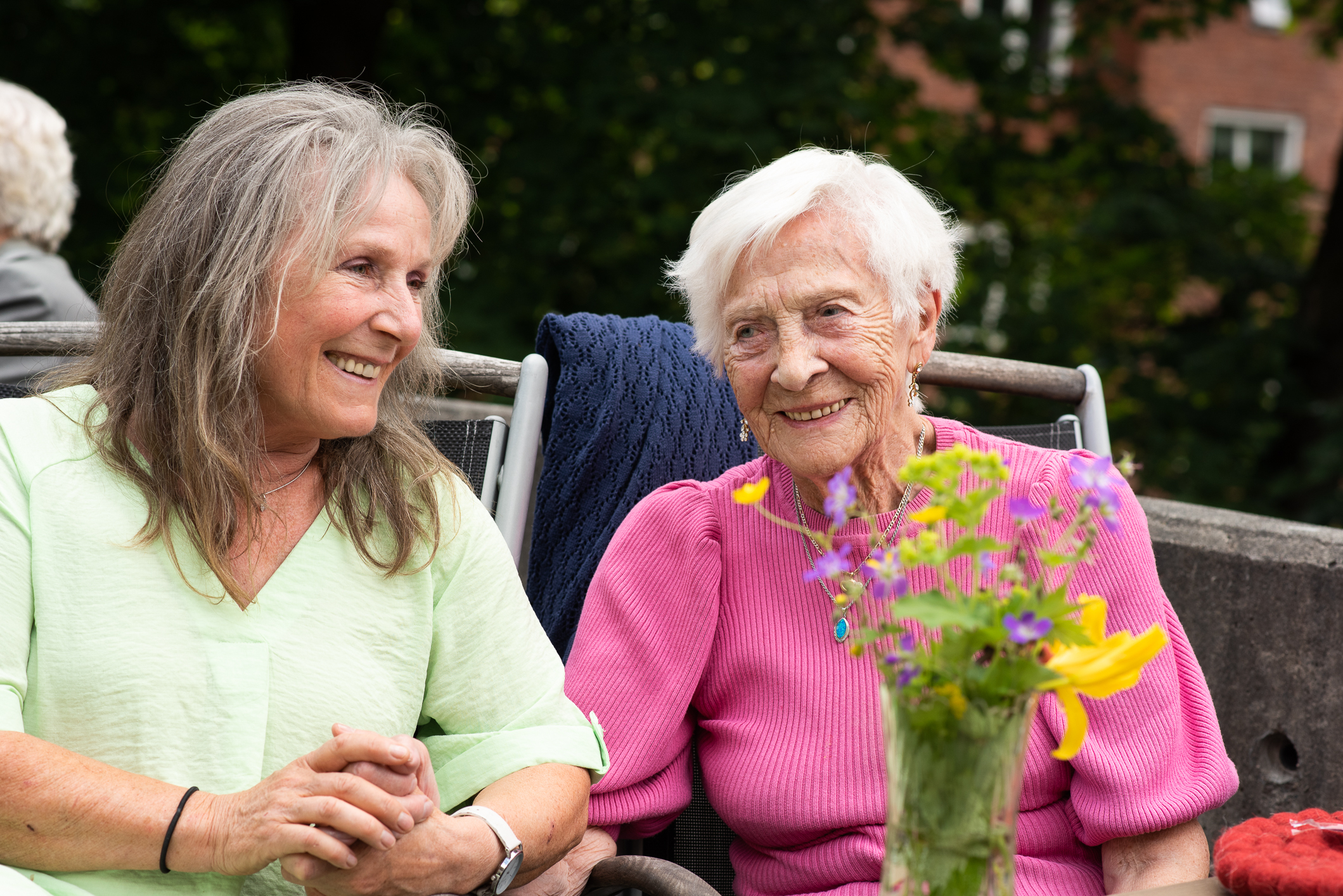 To kvinner sitter ute i hagen