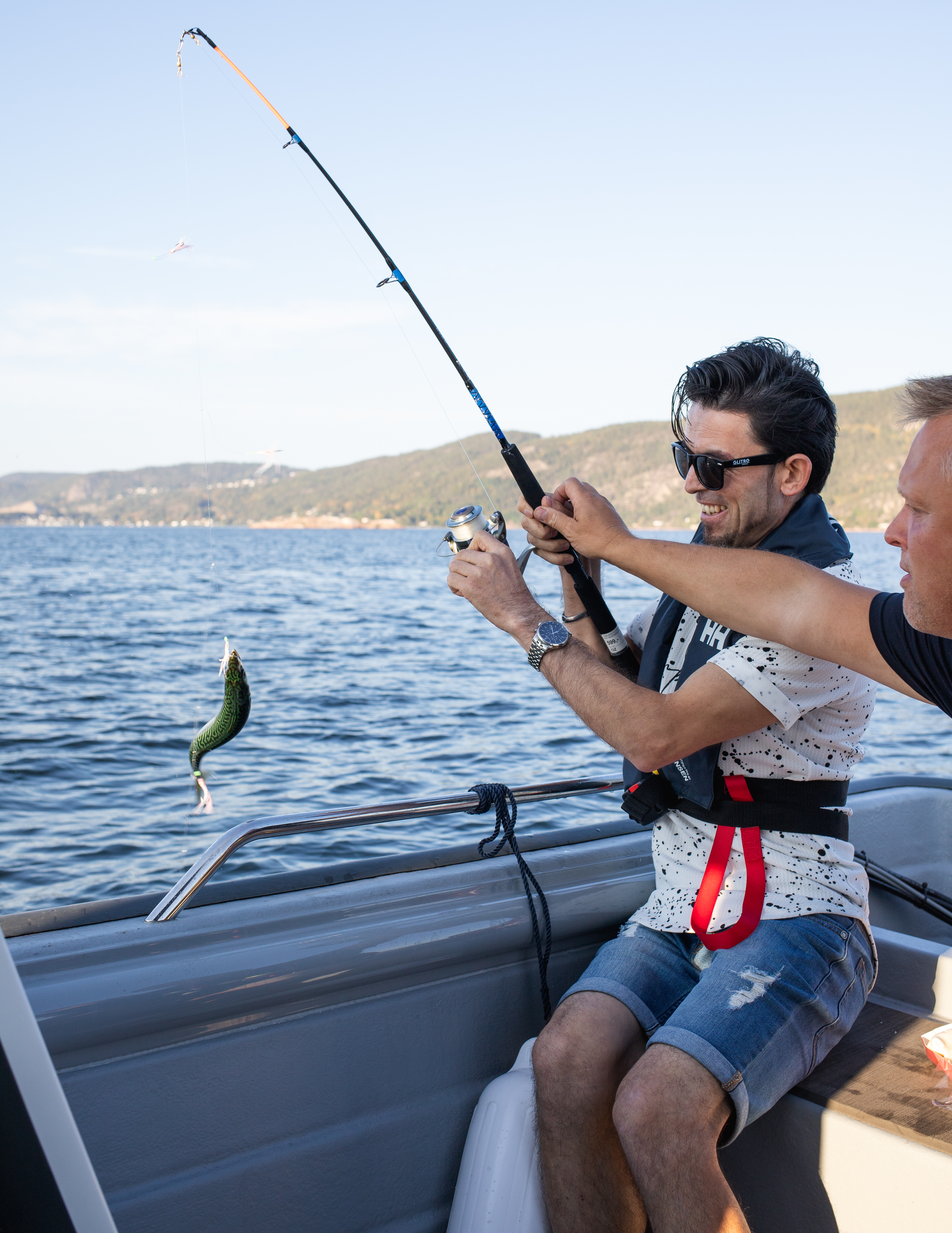 Deltagerne drar opp fisk med fiskestang fra båten