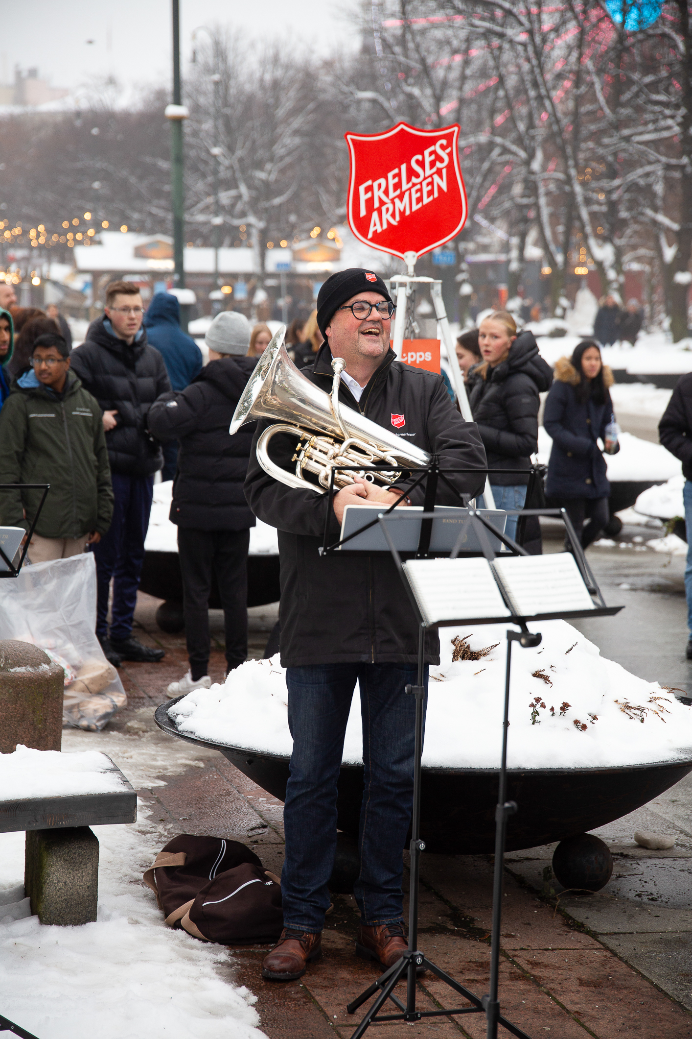 Musikant med en eufonium. I bakgrunnen Frelsesarmeens julegryte med stativ og mange mennesker.