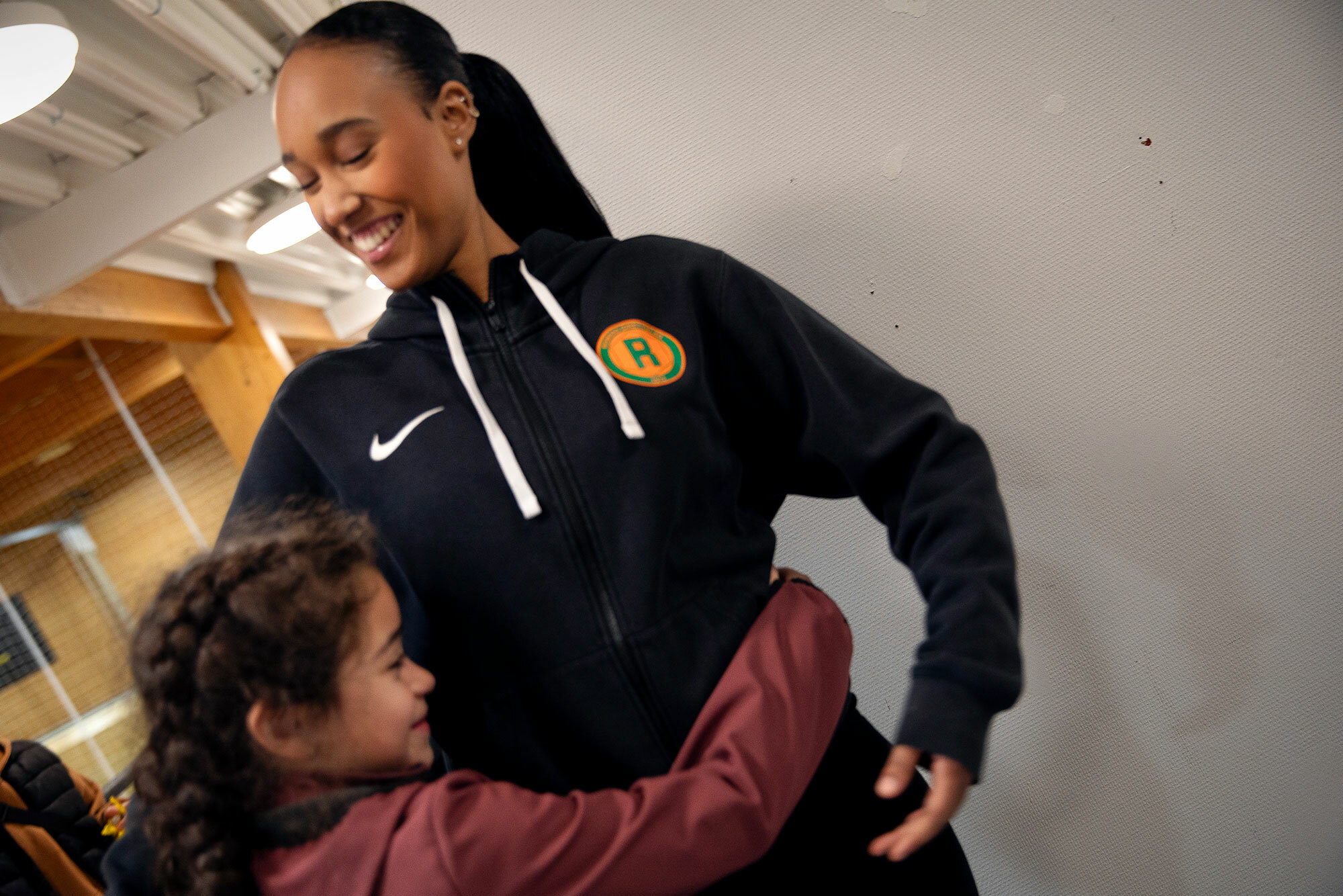 Foto: Liten jente som klemmer en ungdom i blå hettegenser fra Romsås IL.