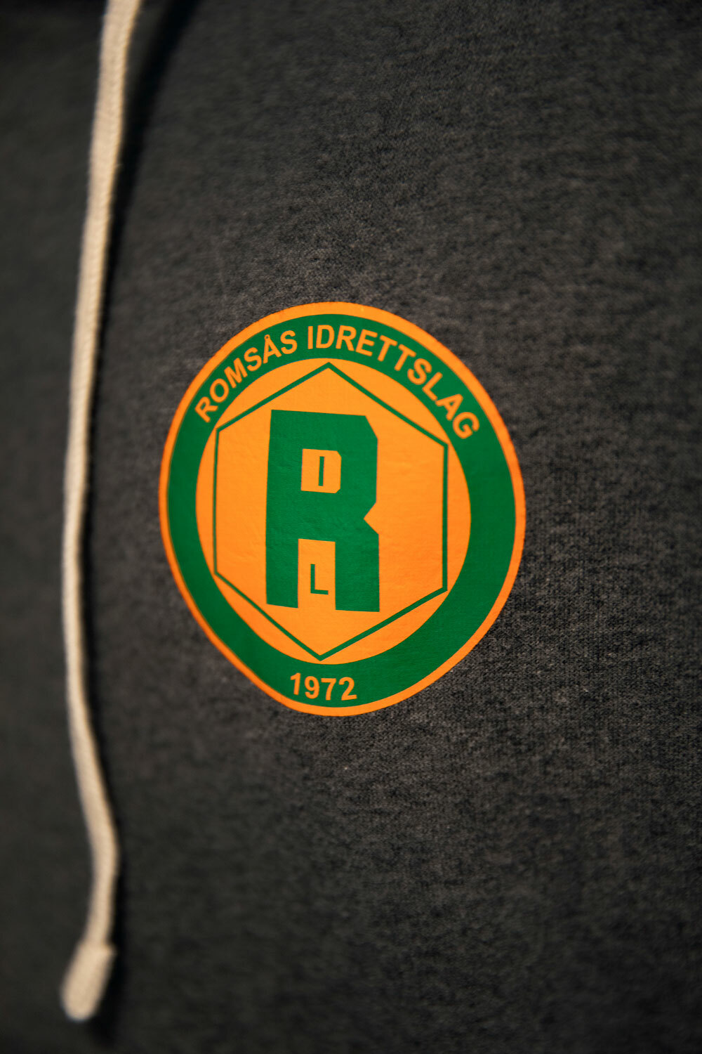 Foto: Logo av Romsås IL på grå hettegenser.
