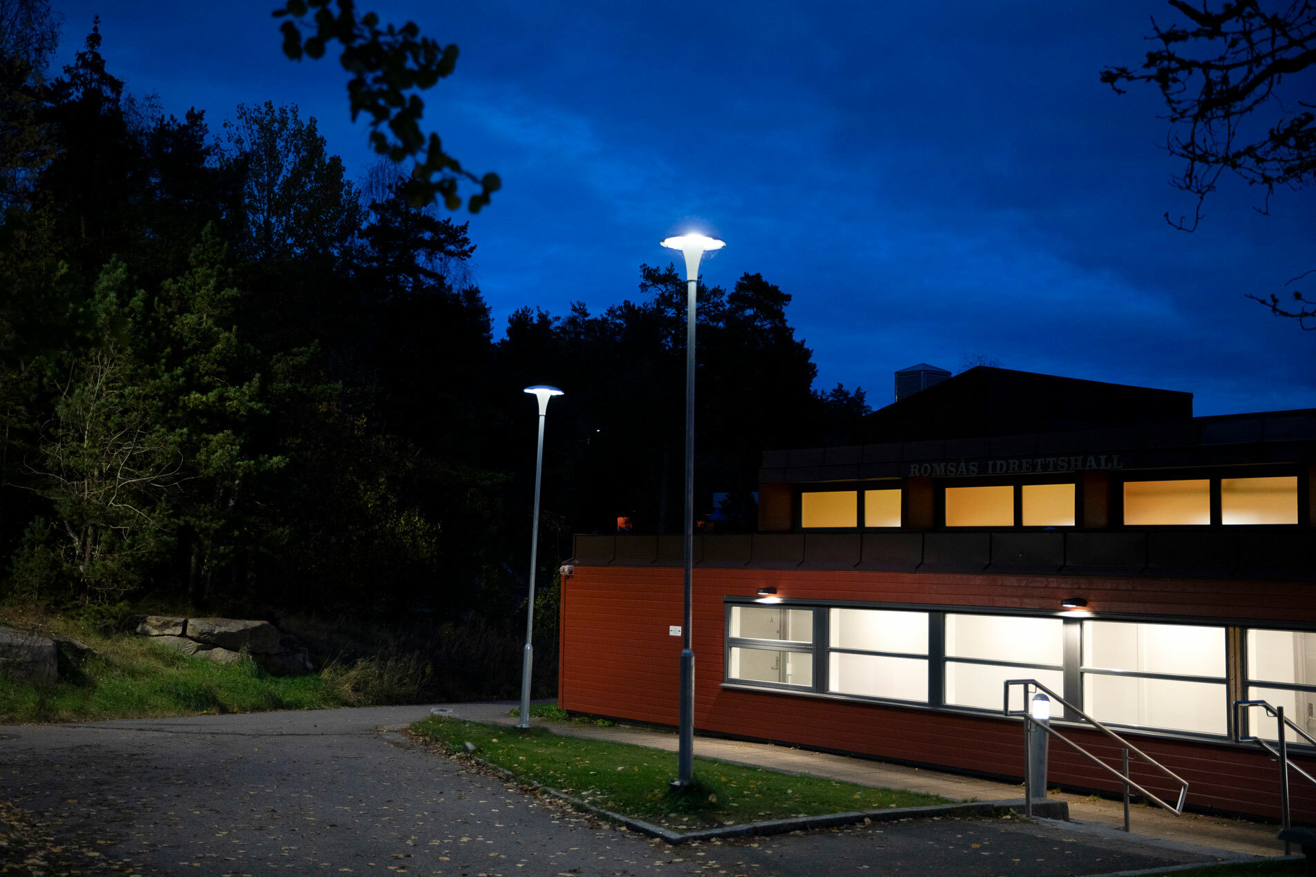 Foto: I kveldsmørket ser vi deler av en idrettshall med lys i.