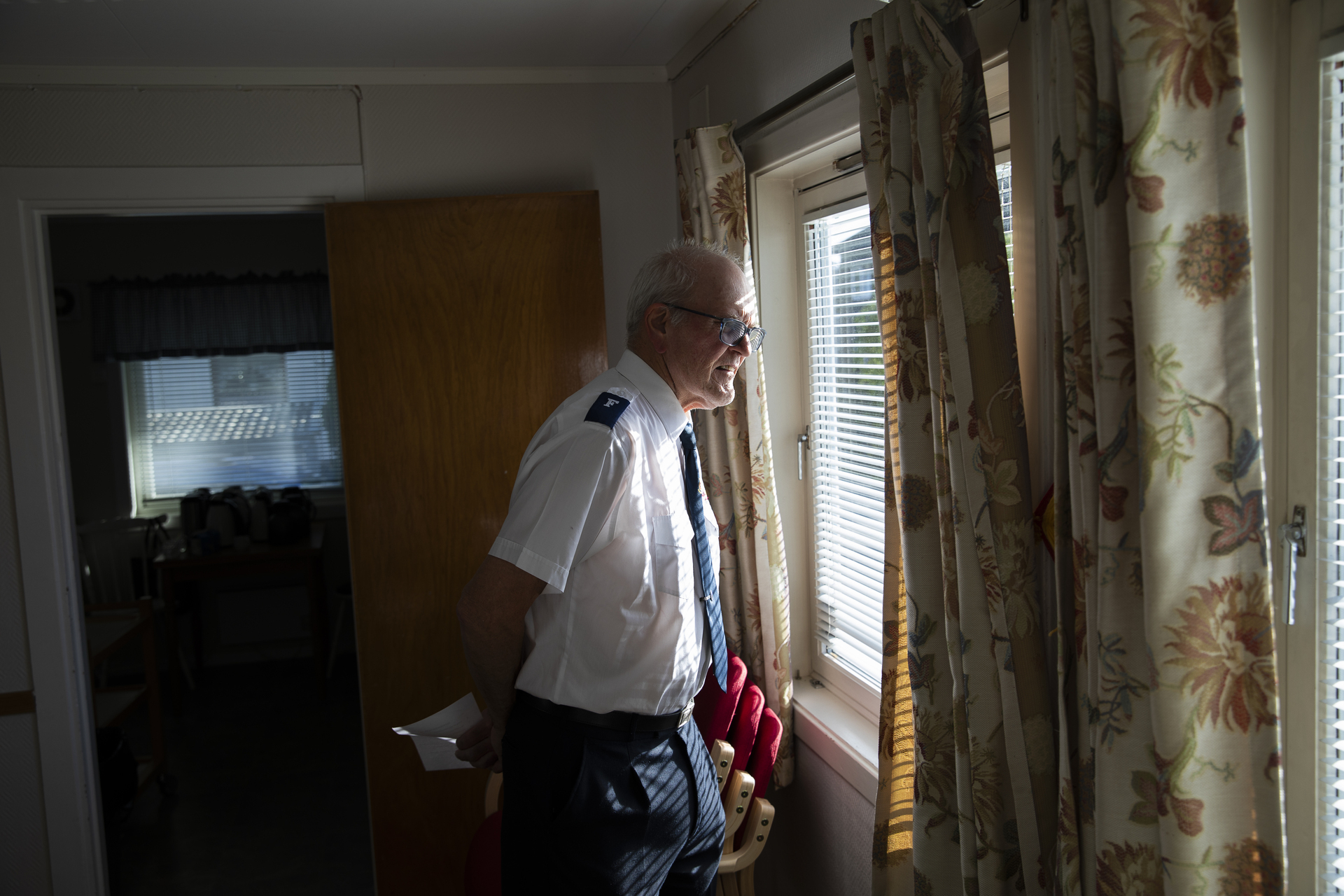 Mann i Frelsesarméuniform sikker ut av vinduet.