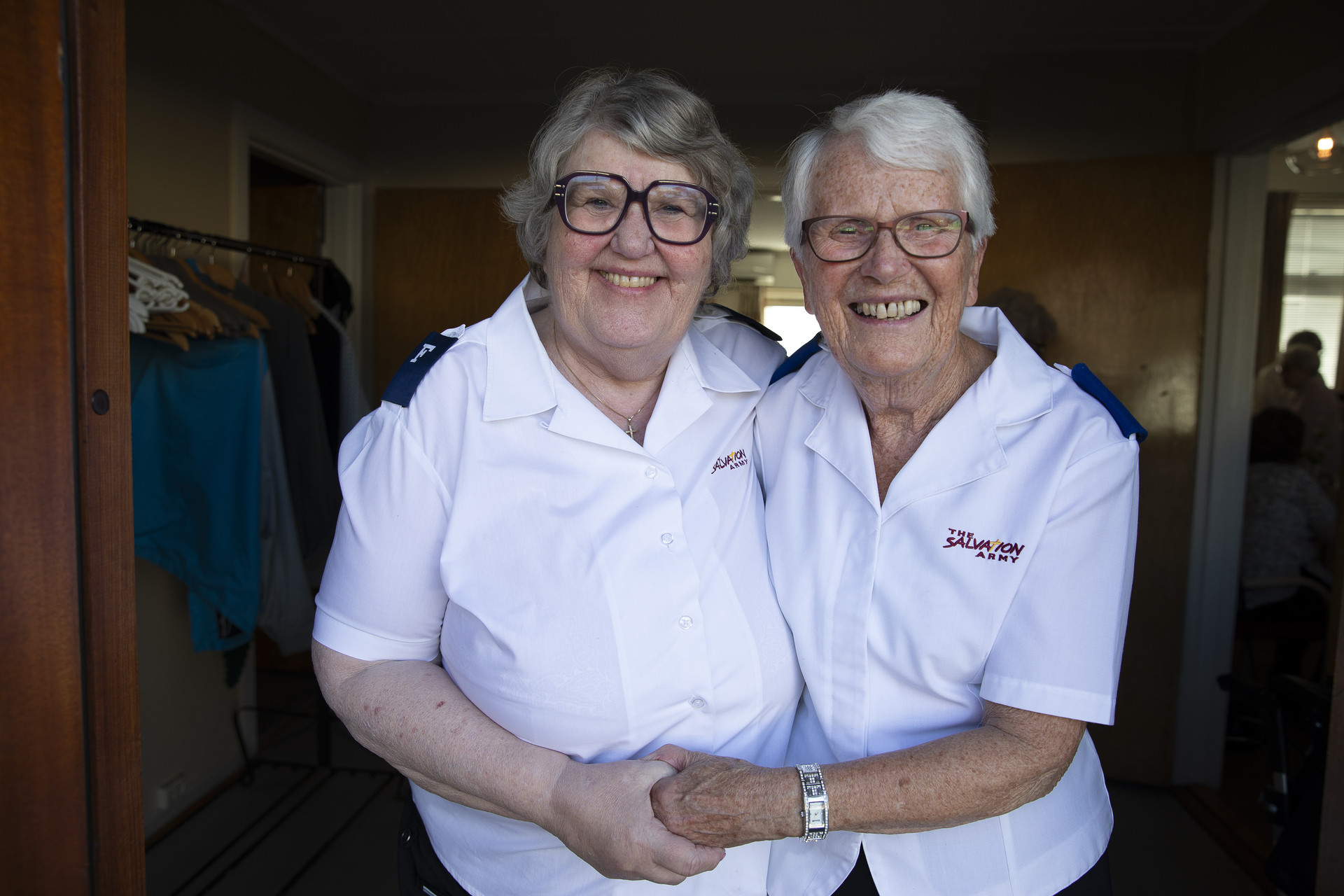 To smilende damer i hvite frelsesarméuniformer.