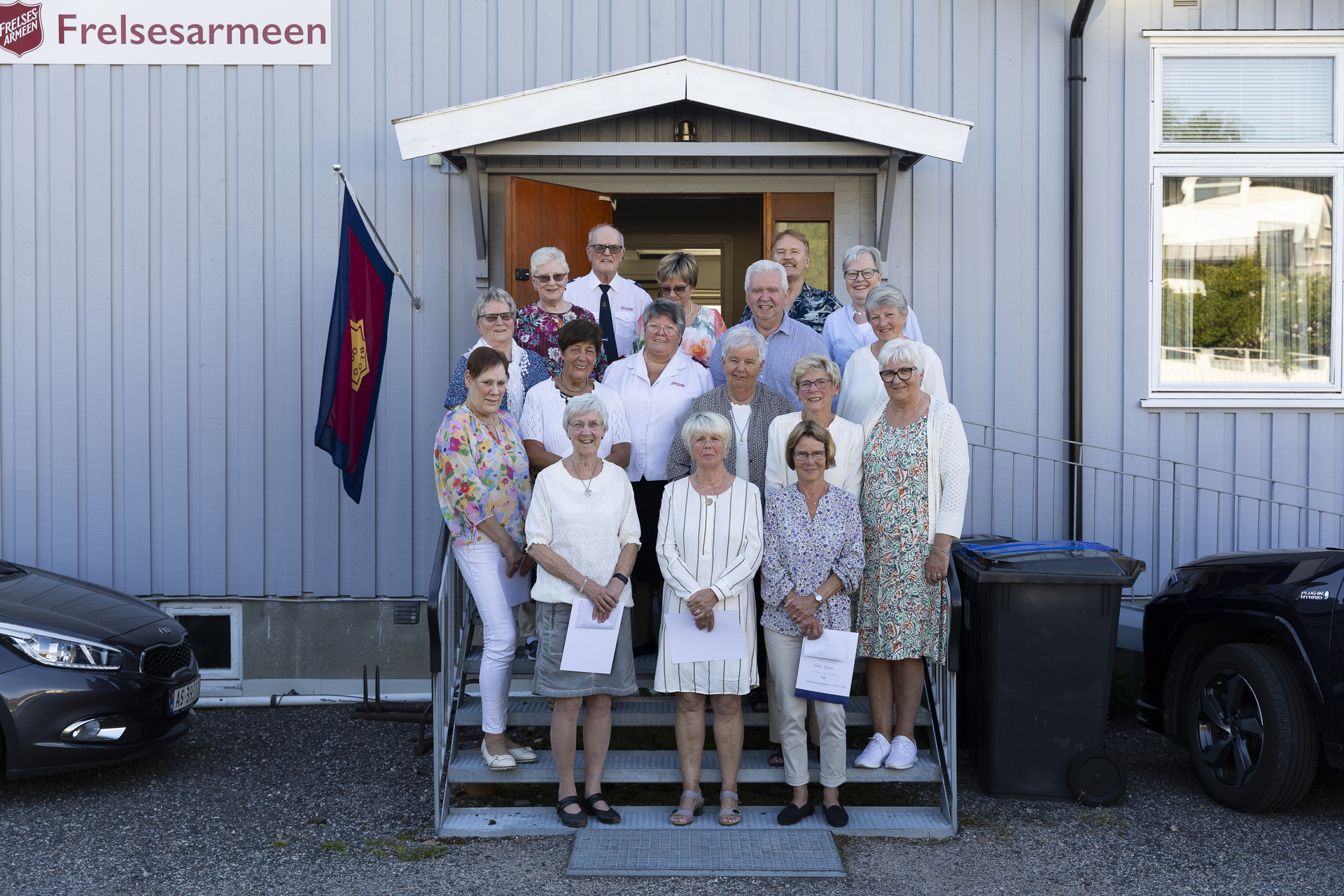 En gruppe mennesker oppstilt i en trapp utenfor et lokale.