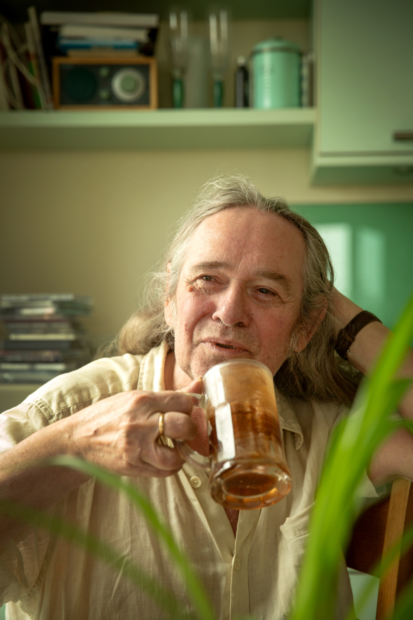 Foto: Mann drikker en kopp med te i gjennomsiktig glass. Han sitter på kjøkkenet.