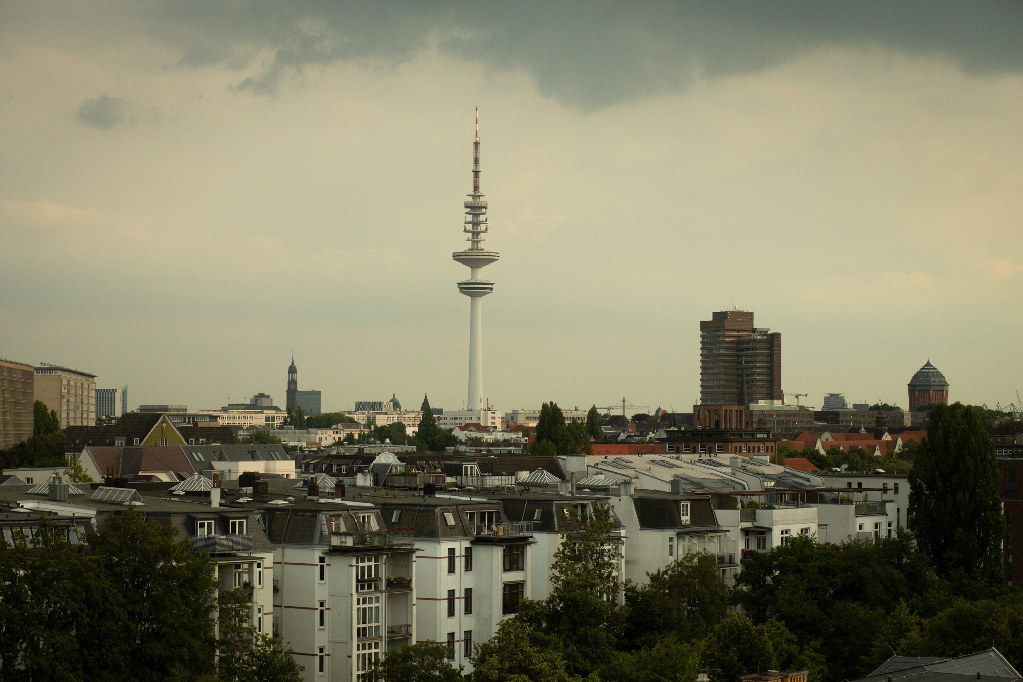 Foto: Utsikt over bybebyggelse med mange blokker. Midt på bildet stikker det et høyt tårn opp.