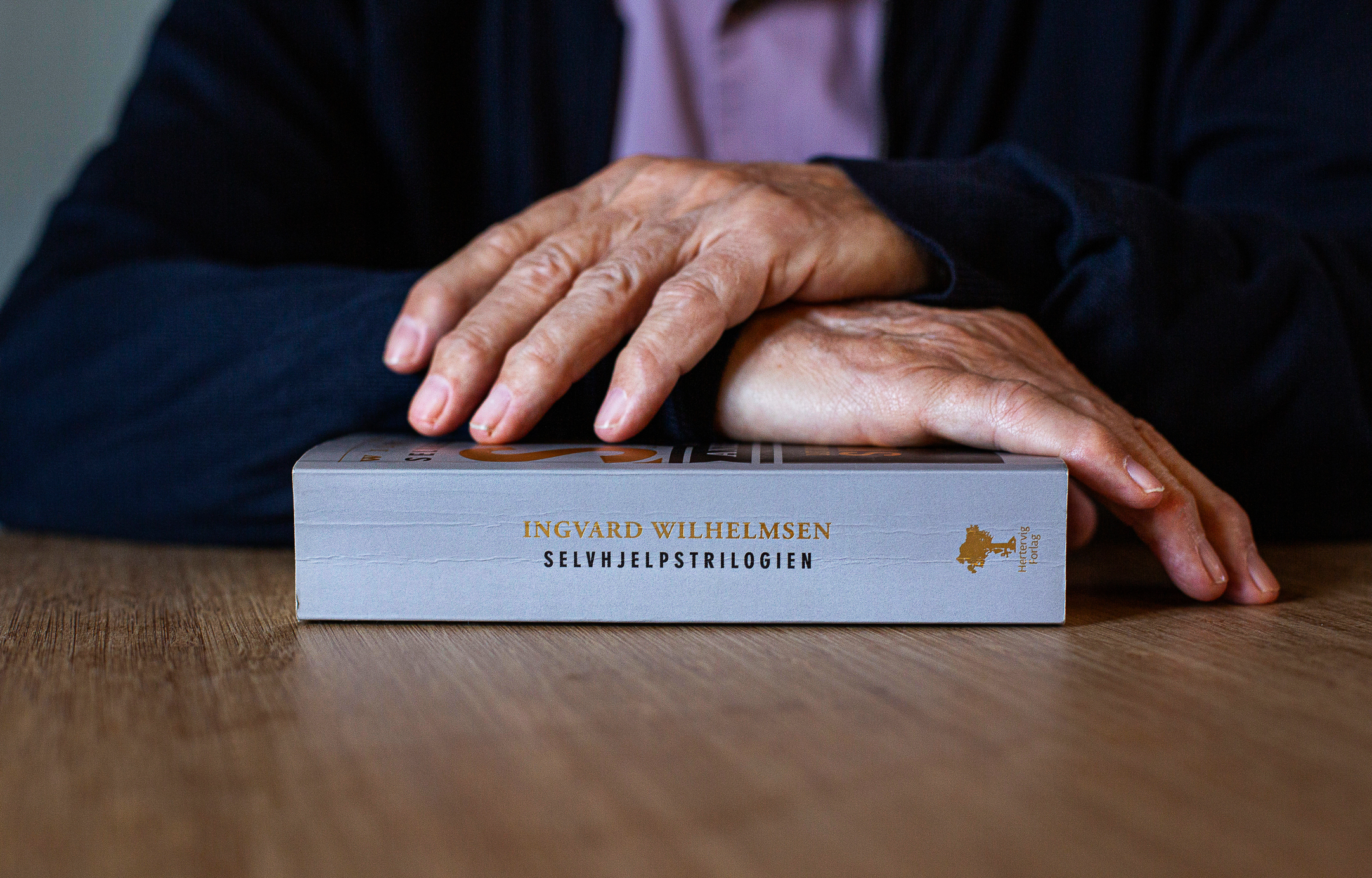 Foto: To gamle hender som ligger oppå en bok.