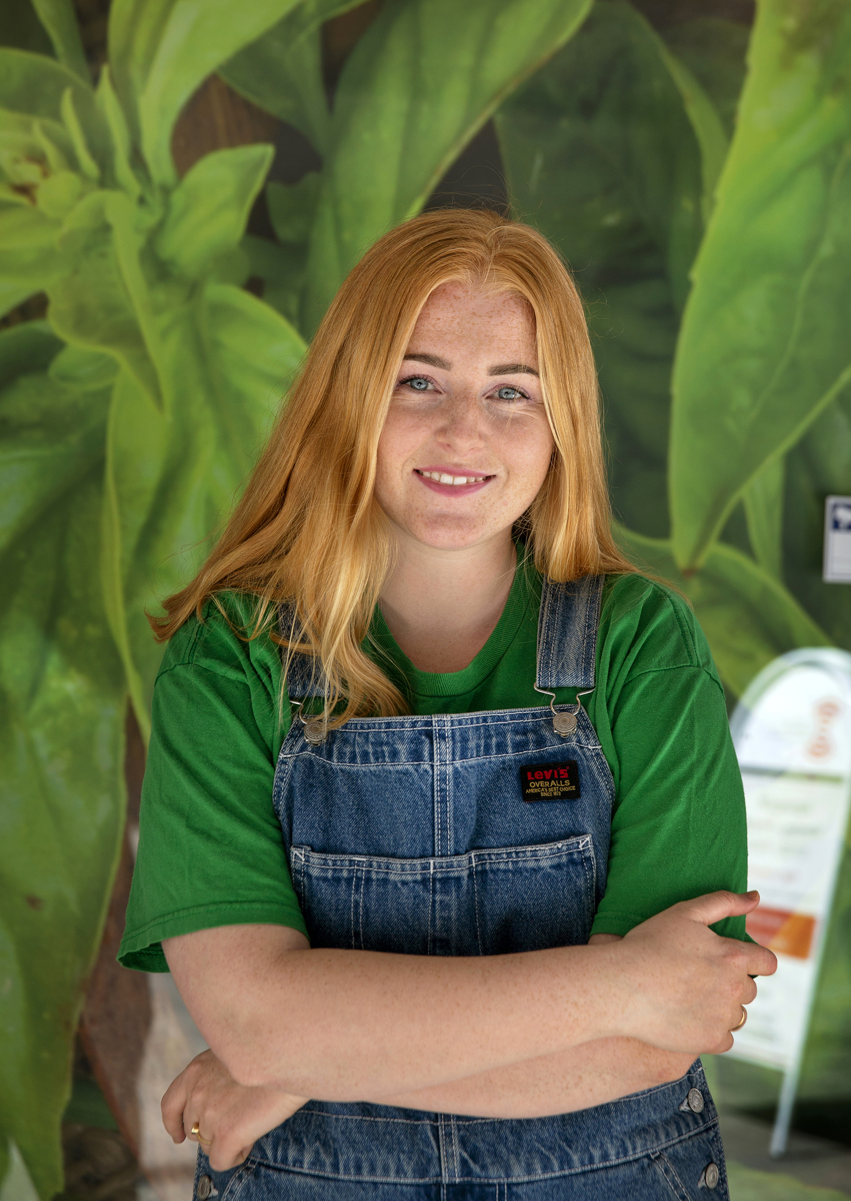 Ivo står smilende foran en stor, grønn plante