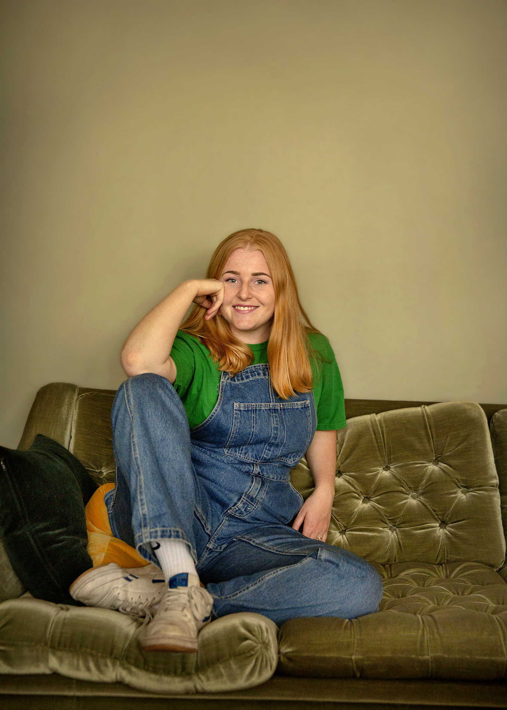 Ivo sitter i en grønn velur sofa med beina oppi sofaen