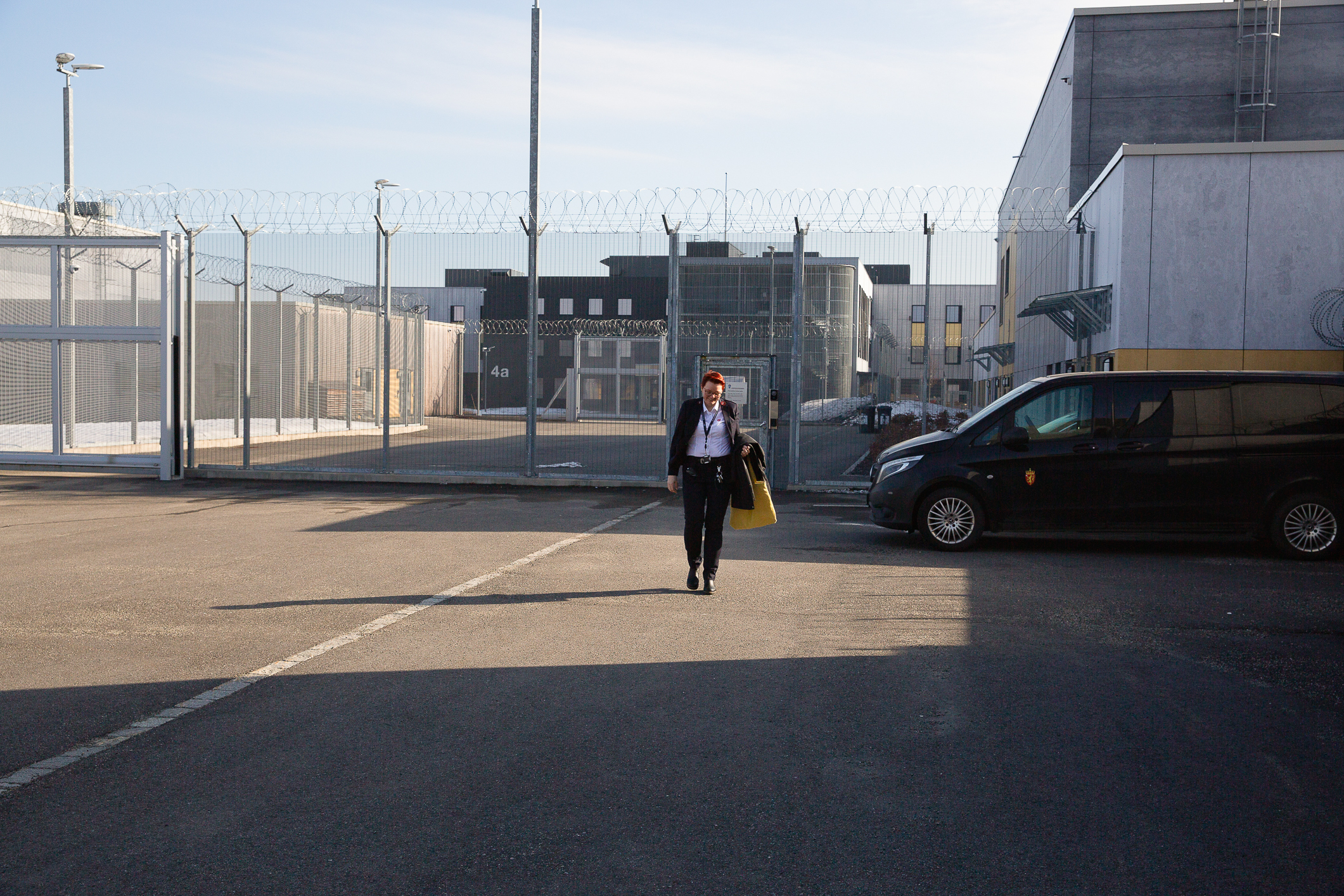 En kvinne i Frelsesarméuniform går  på farkeringsplassen utenfor et fengsel.