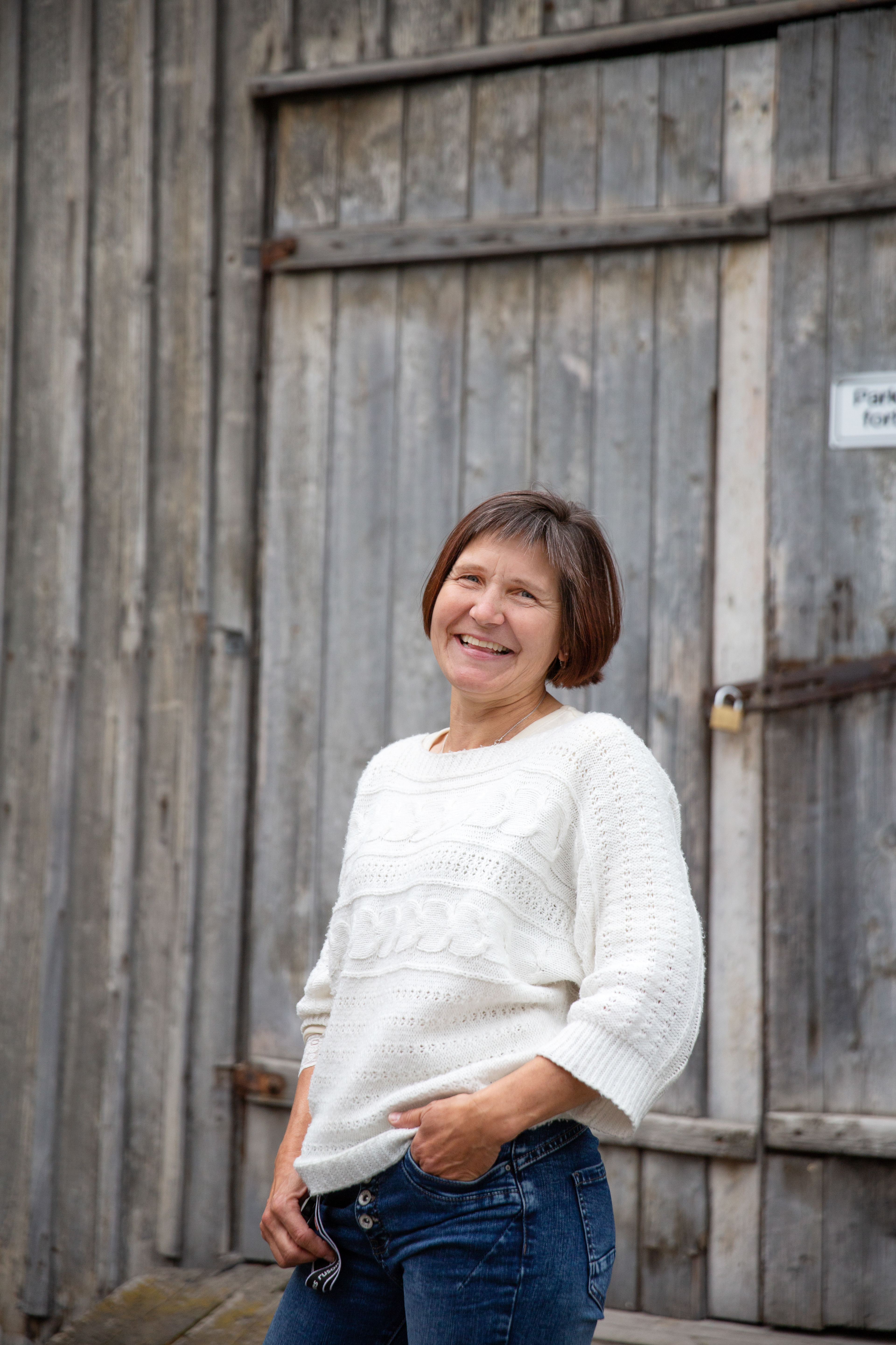 Elisabeth smiler bredt foran en låvedør.