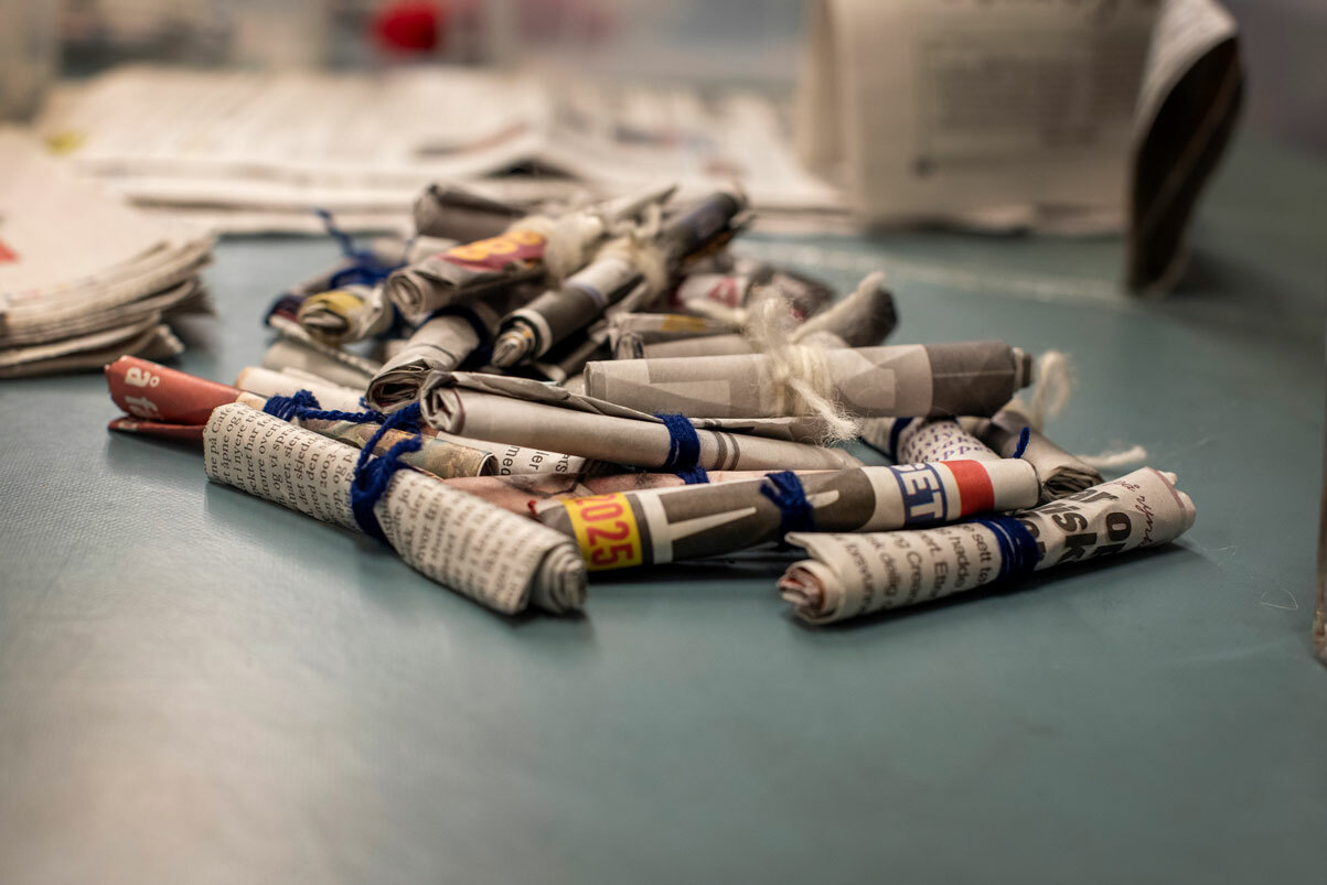 Foto: Tennbriketter av sammenrullet avispapir ligger utover et bord.