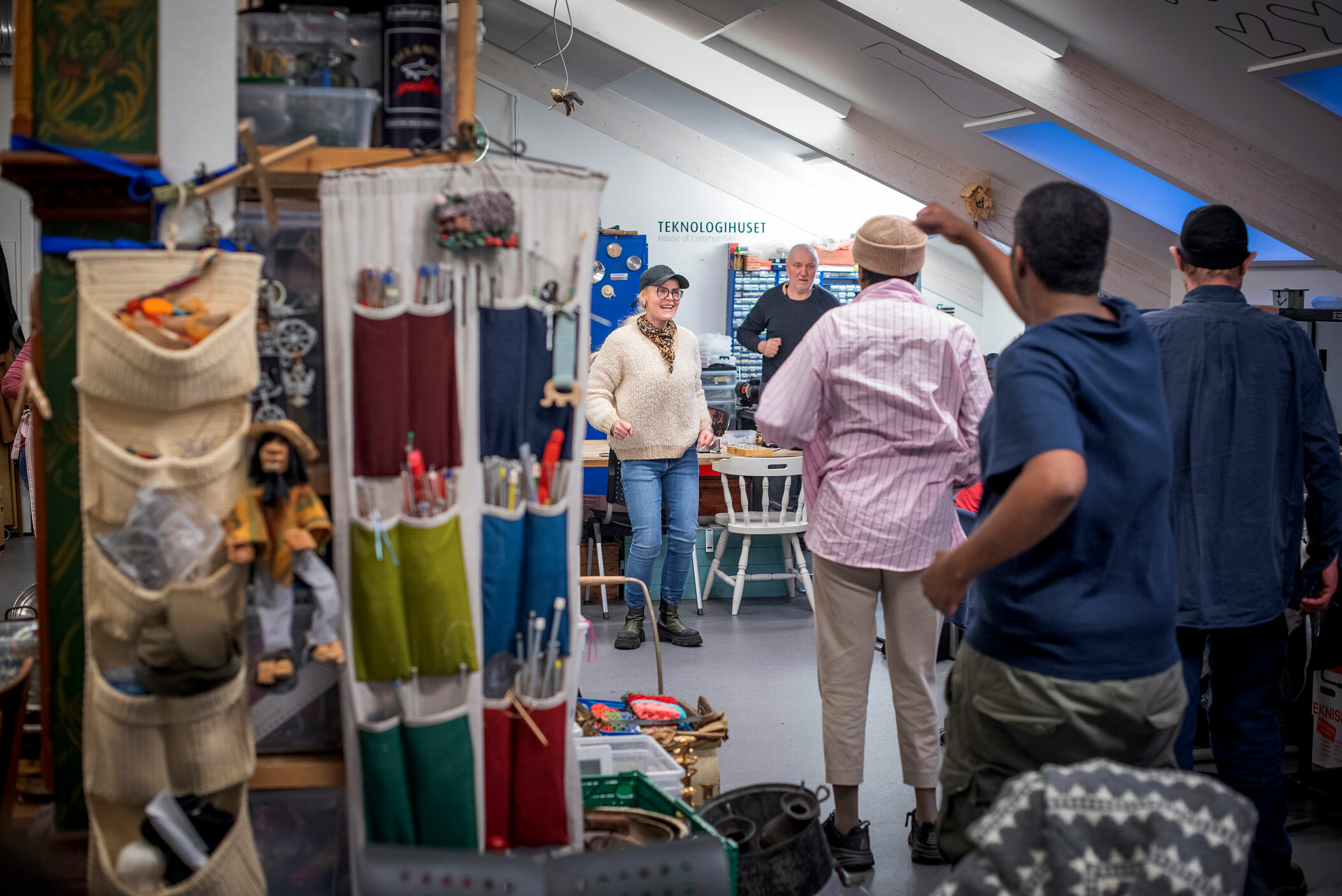 Foto: Inne på en systue med skråtak strekker fem personer på seg.