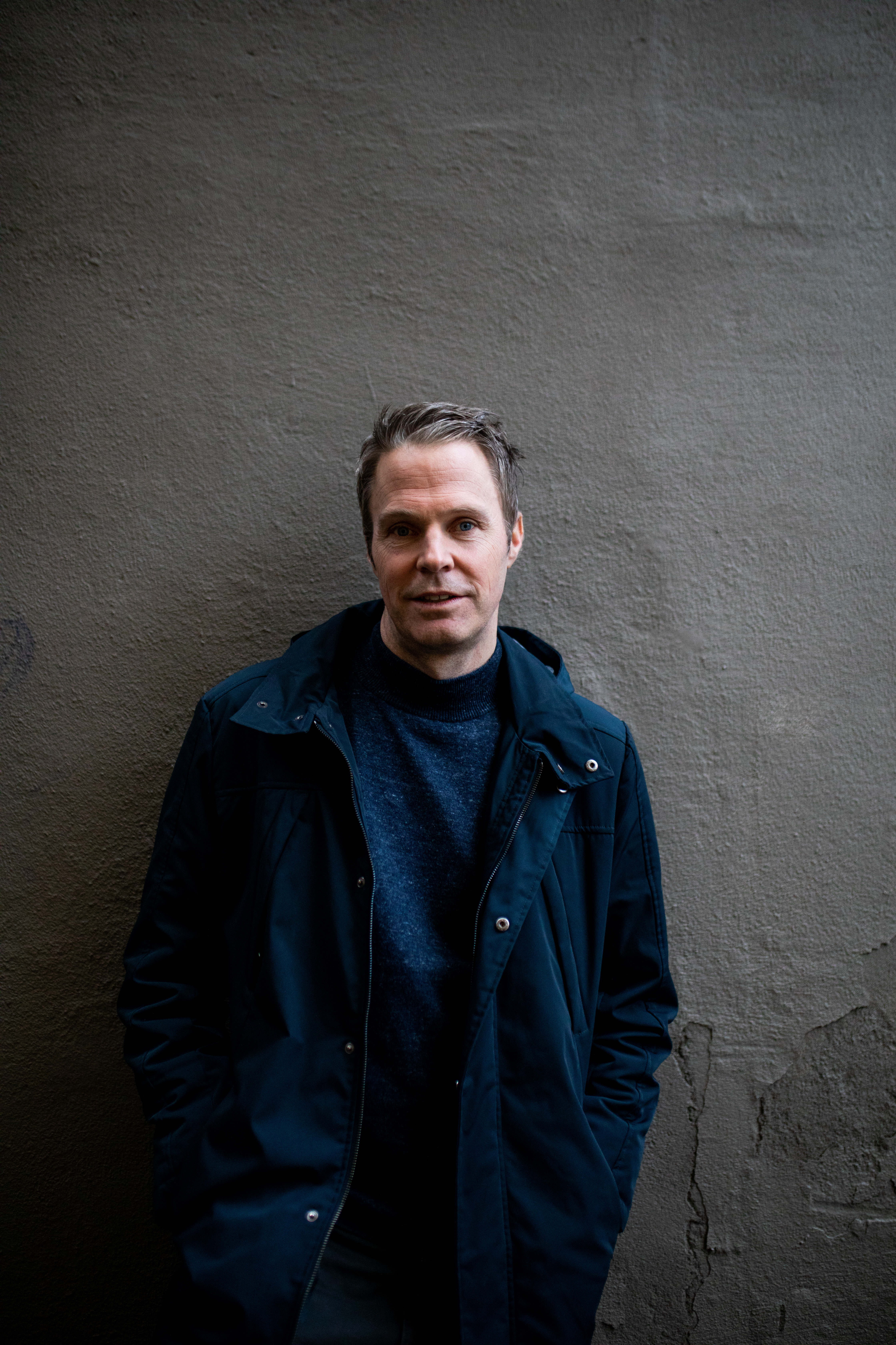 Jostein Ørum står foran en grå betongvegg. Han har en åpen vårjakke med en ullgenser under.