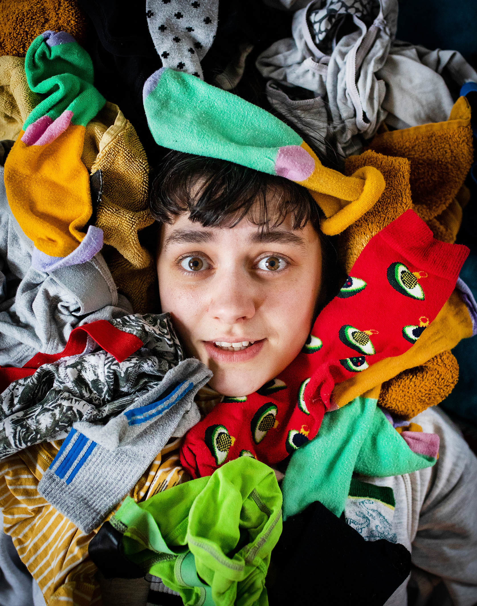 Julie ligger på gulvet omringet av mange fargerike sokker