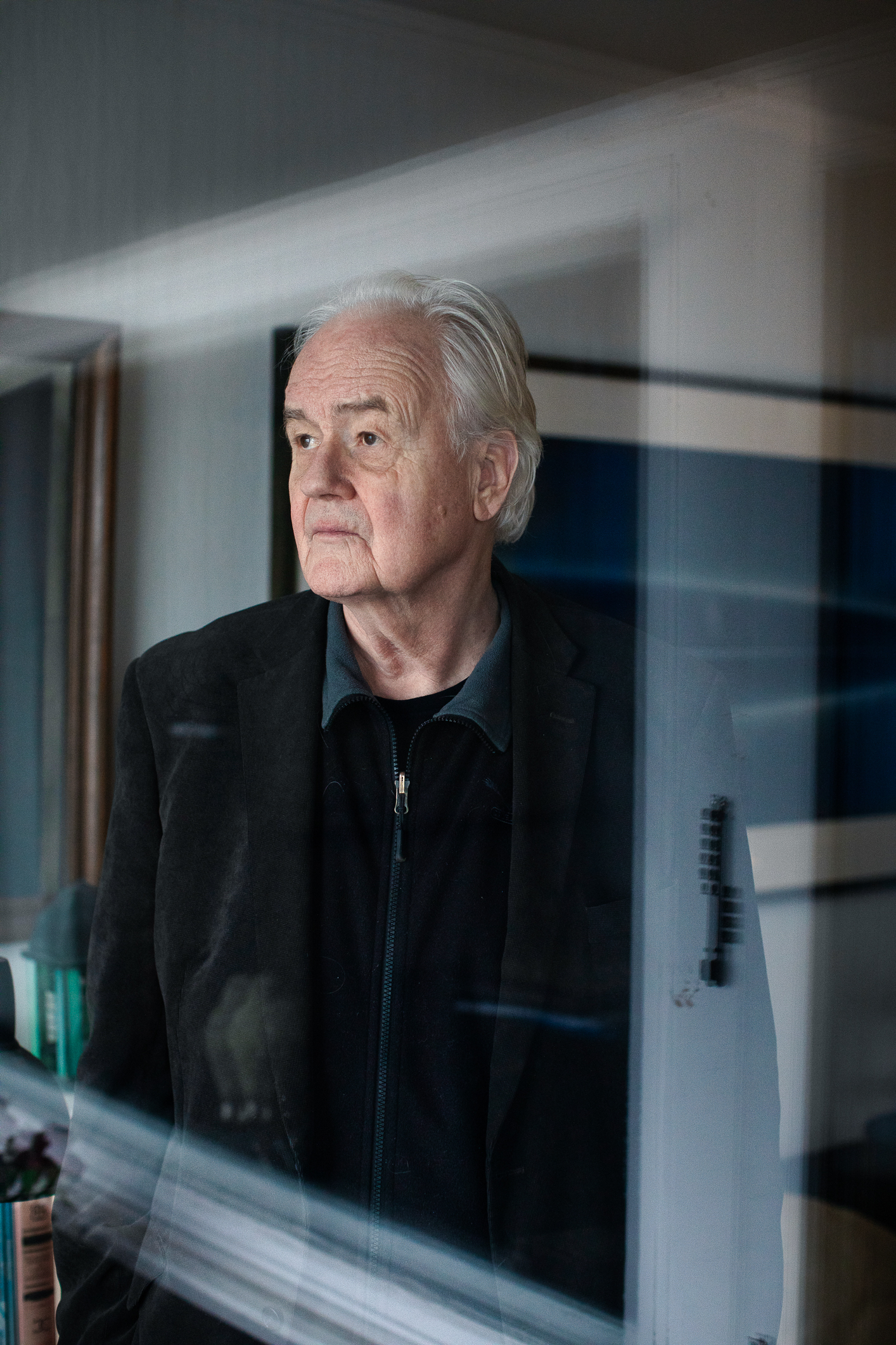 Gammel mann som kikker ut av vinduet. Bildet er tatt fra utsiden.