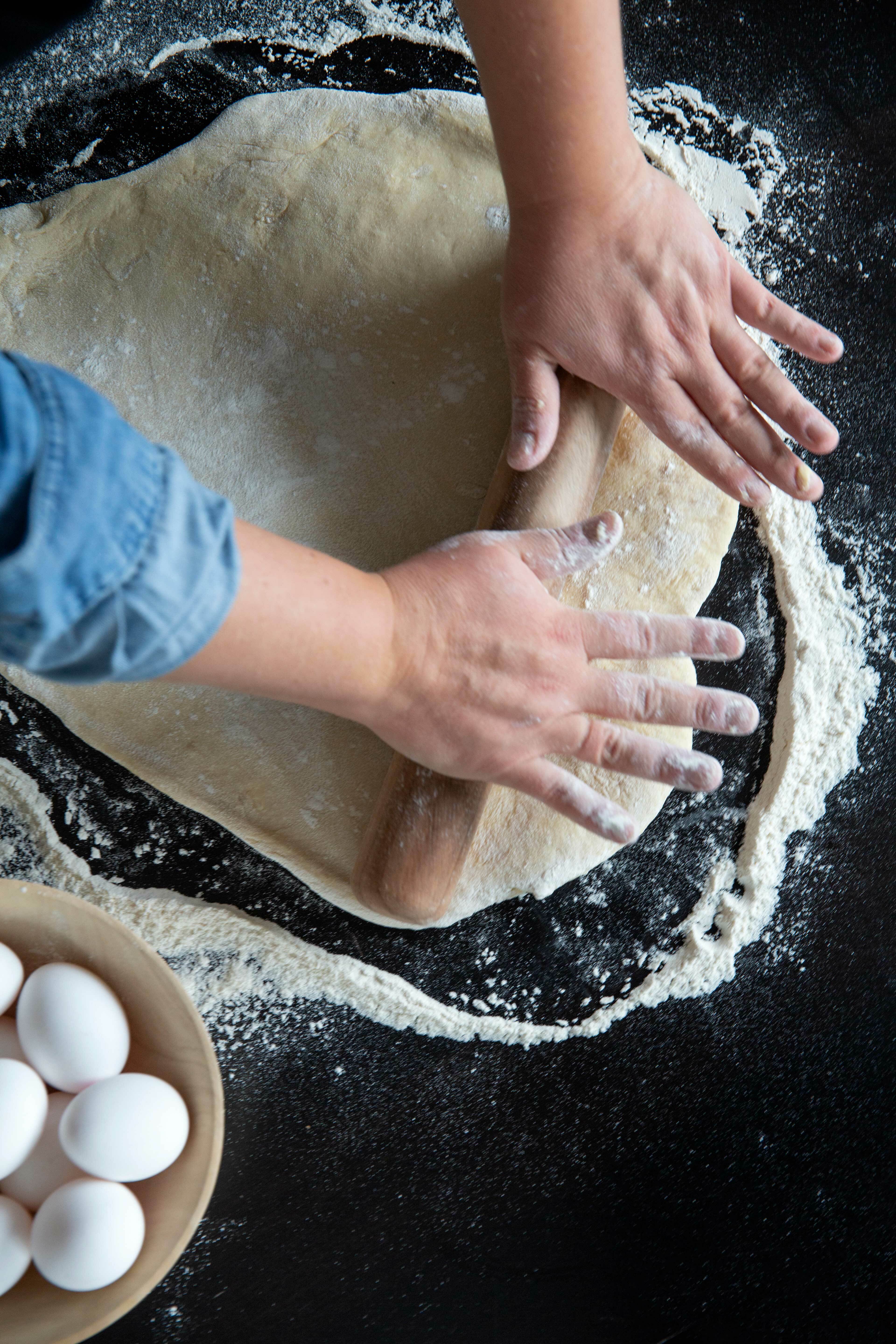 Hender som kjevler deig. Egg i en skål