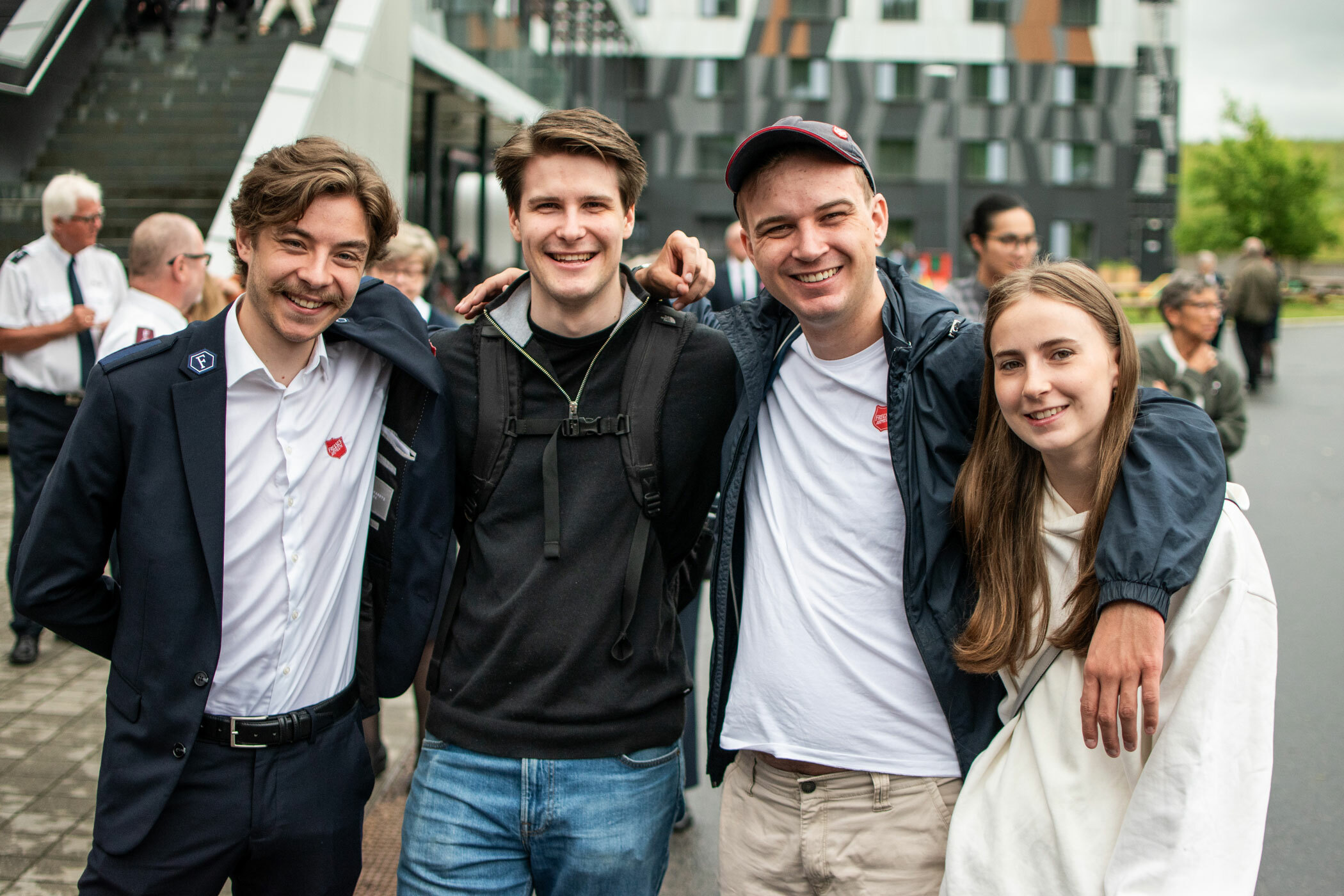 Foto: Fire ungdommer står på rekke og holder rundt hverandre. Tre er unge menn og den siste en tenåringsjente med mørkt, langt hår. En av gutta har på seg hvit skjorte og uniform fra Frelsesarmeen.