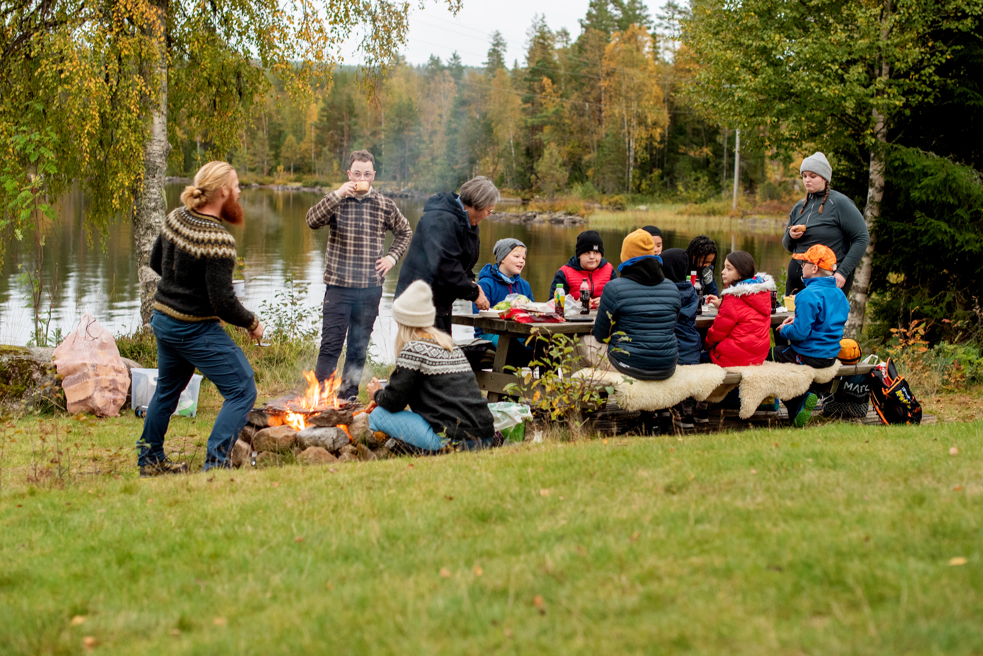 Deltakere og ledere griller på bålet og spiser  under åpen himmel