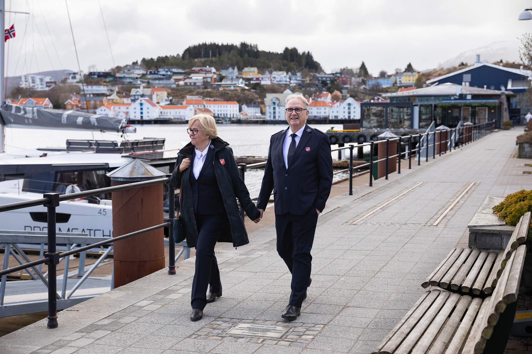 Middelaldrende par går hånd i hånd på bryggepromenaden. Begge har Frelsesarmeens uniformer på seg.