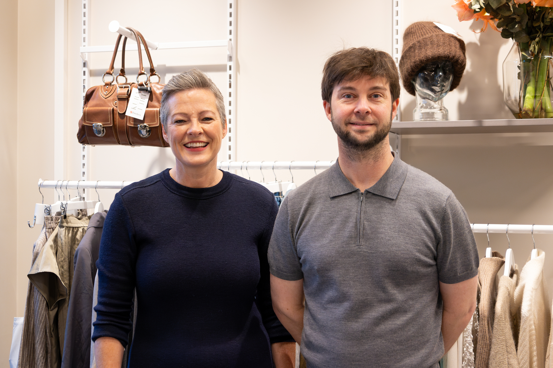 Foto: Ung mann med mørkt hår og skjegg står oppstilt i en butikk ved siden av en kvinne i 50-årene med kort, grå hårsveis.