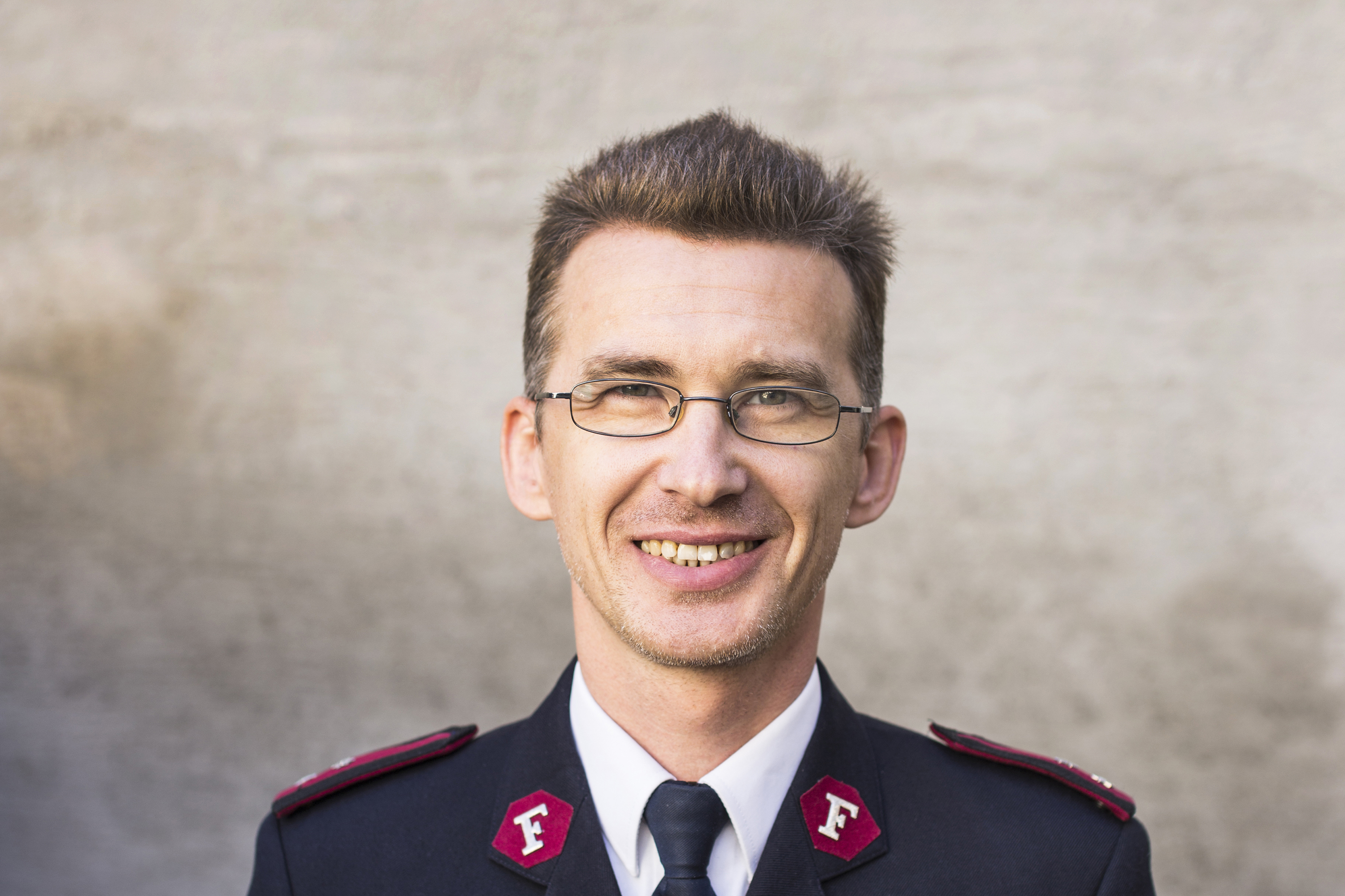 Et nærportrettbilde av en smilende major Yury Zelentsov. Han er ikledd Frelsesarmeens uniform og smiler til fotografen.