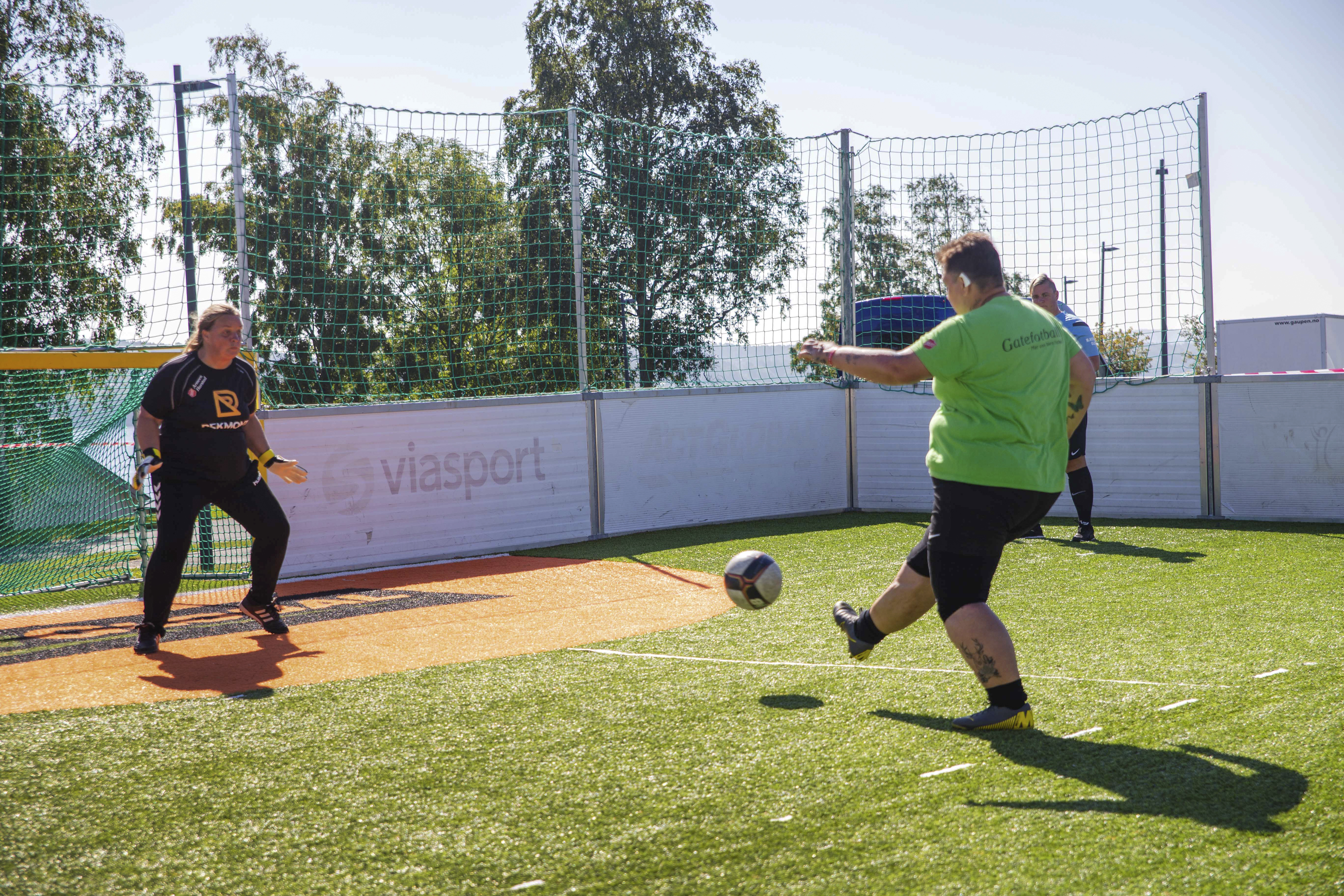 Bildet viser Linda som skyter en fotball mot mål. En målvakt i svarte klær står i bakgrunnen.