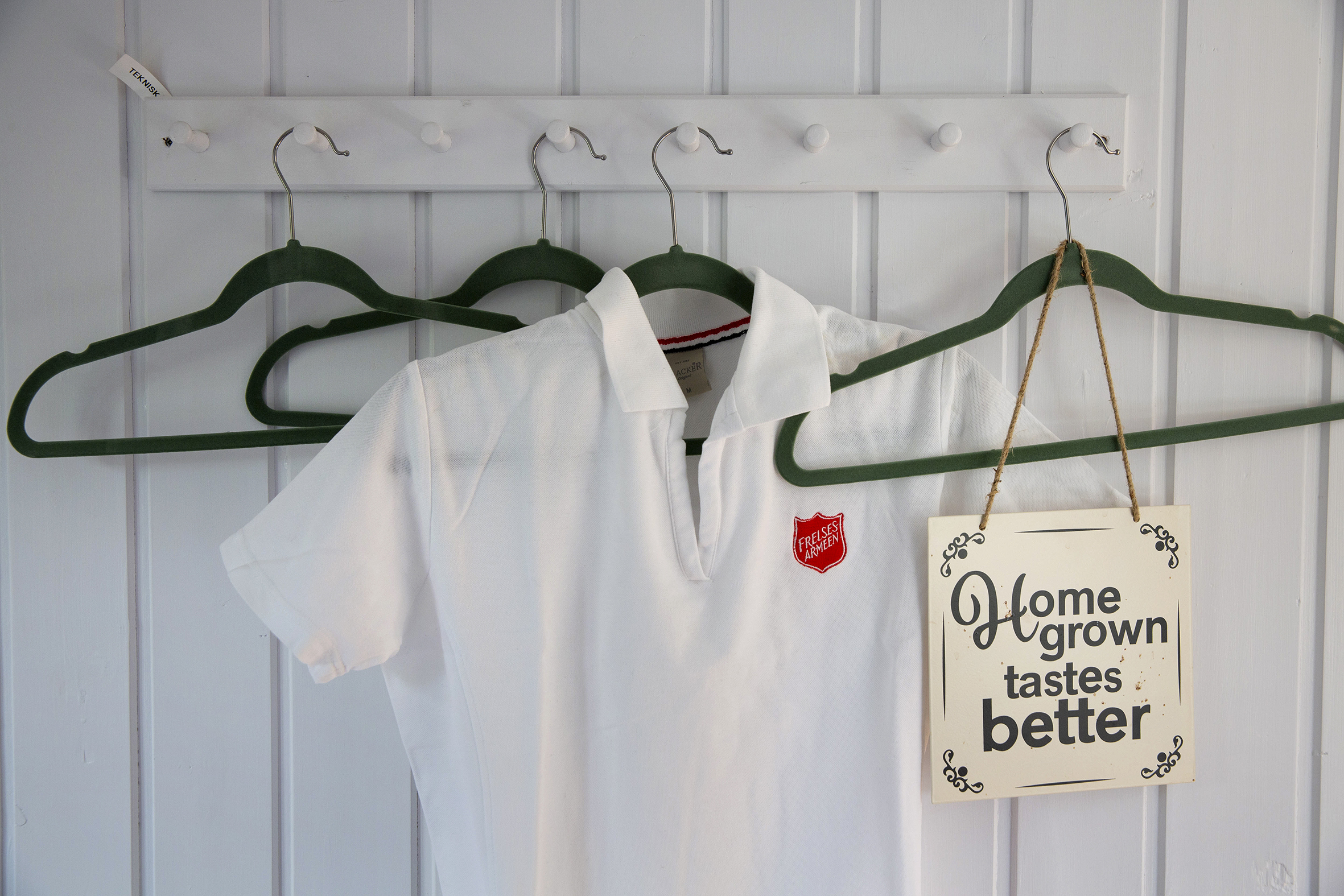 Prestekrager i kolonihagen og t-shirt med Frelsesarmeen skjoldet på en knaggrekke inne i hytta.
