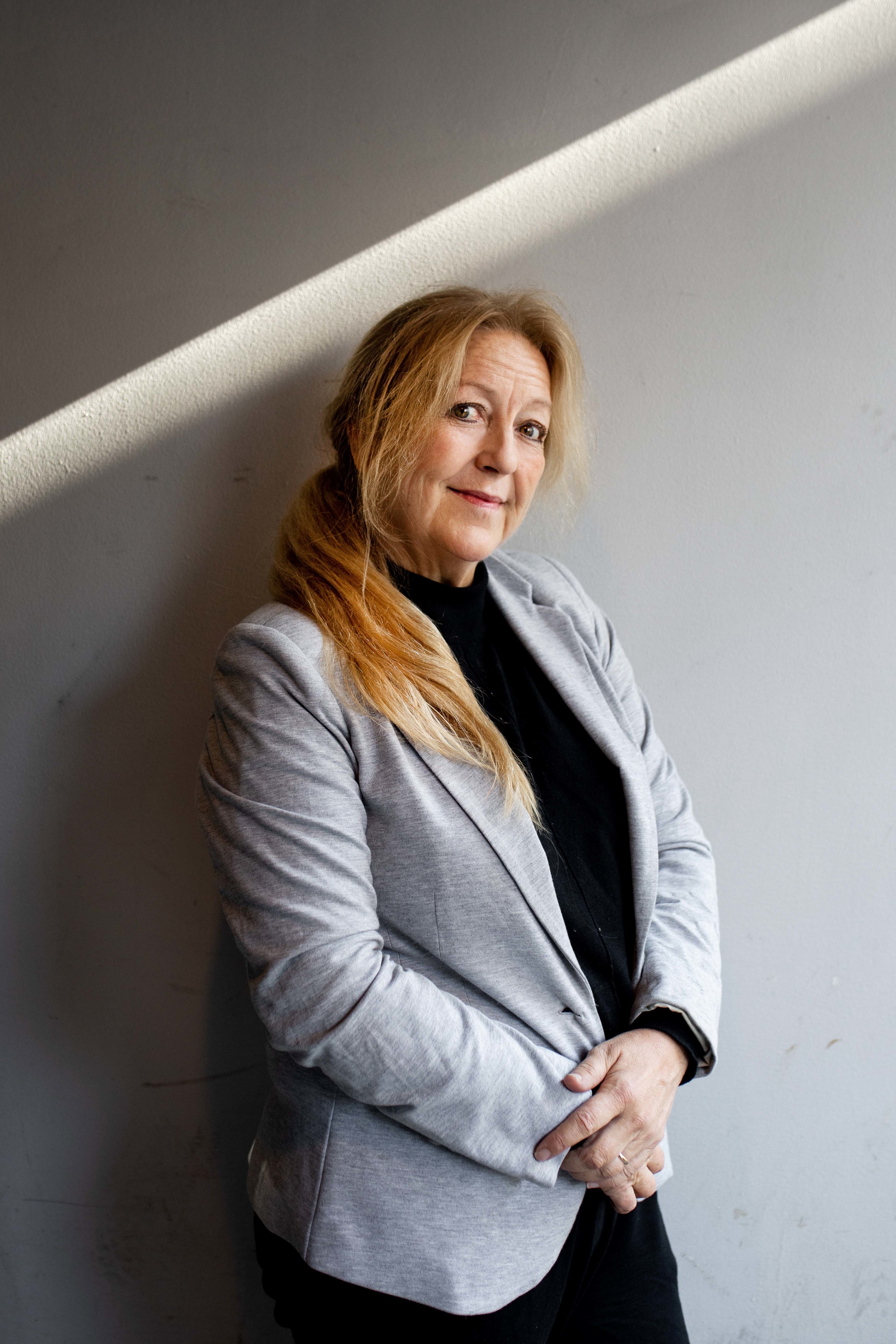 Lovise Angen Krogstad, psykolog og artist, har på seg sort genser og grå jakke, lent opp mot en går murvegg