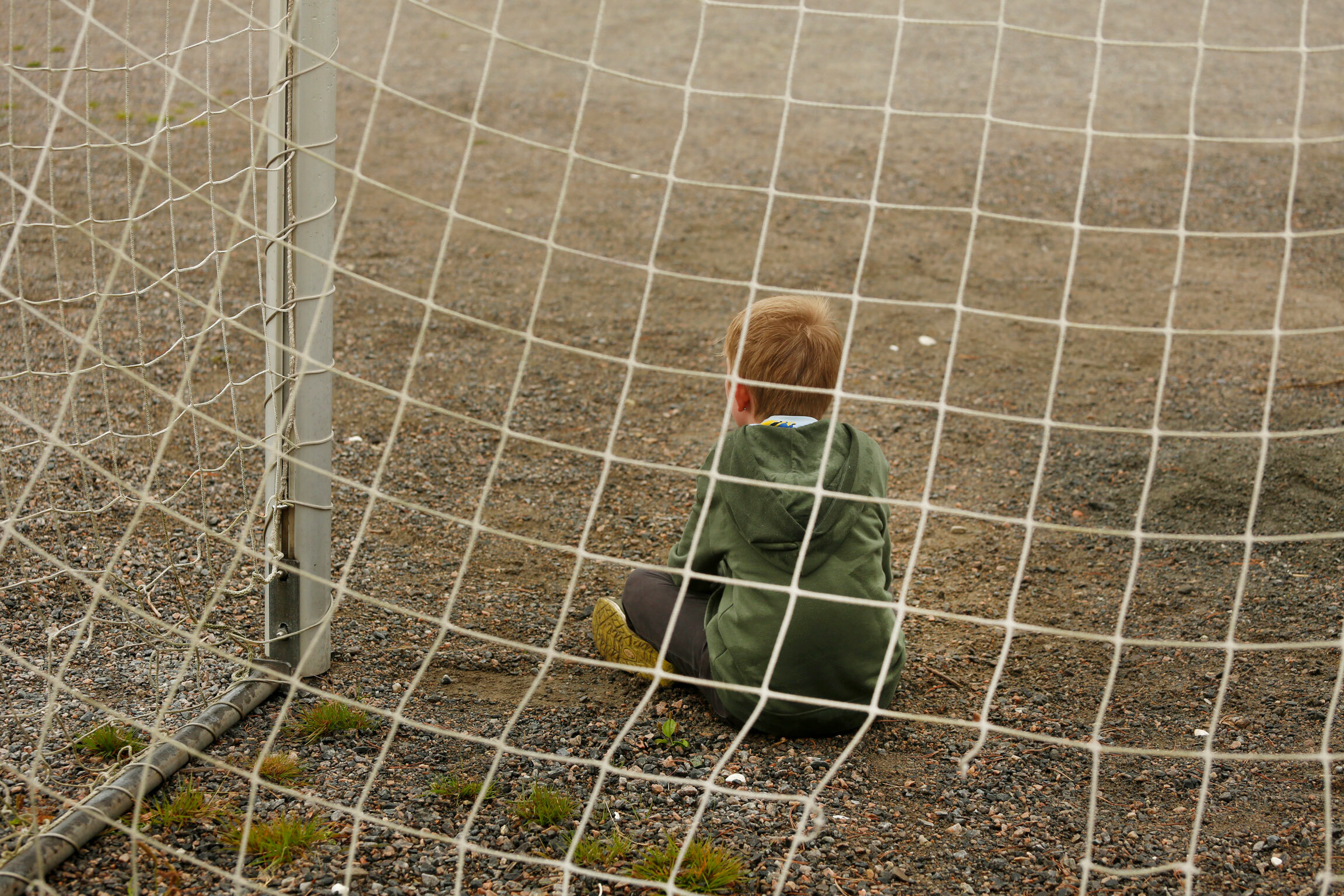 Foto: Gutt på rundt ti år sitter med ryggen til alene i et stort fotballmål. Ingen å leke med.