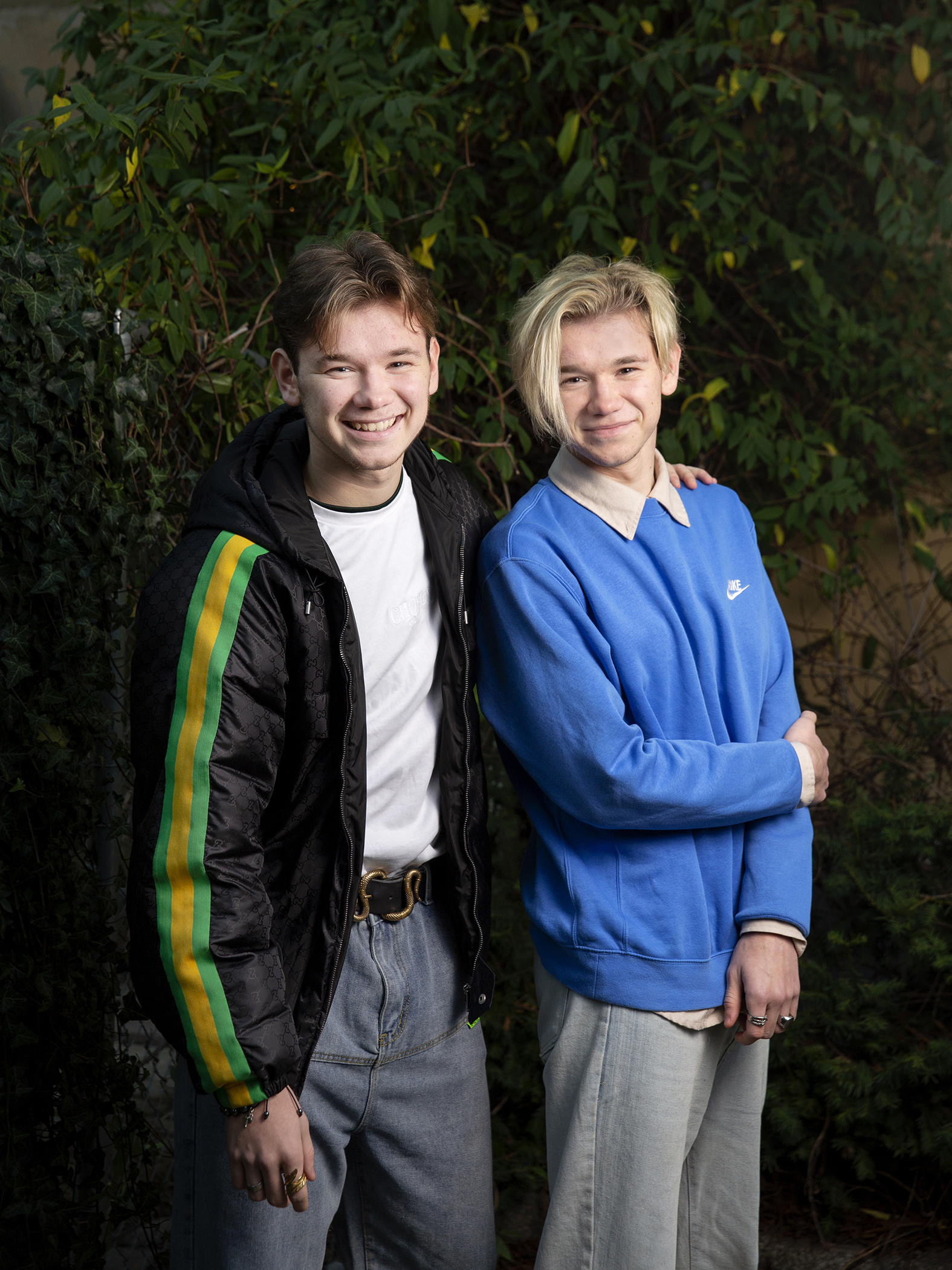 Bilde av tvillingene og artistene Marcus og Martinus foran en murvegg utendørs.