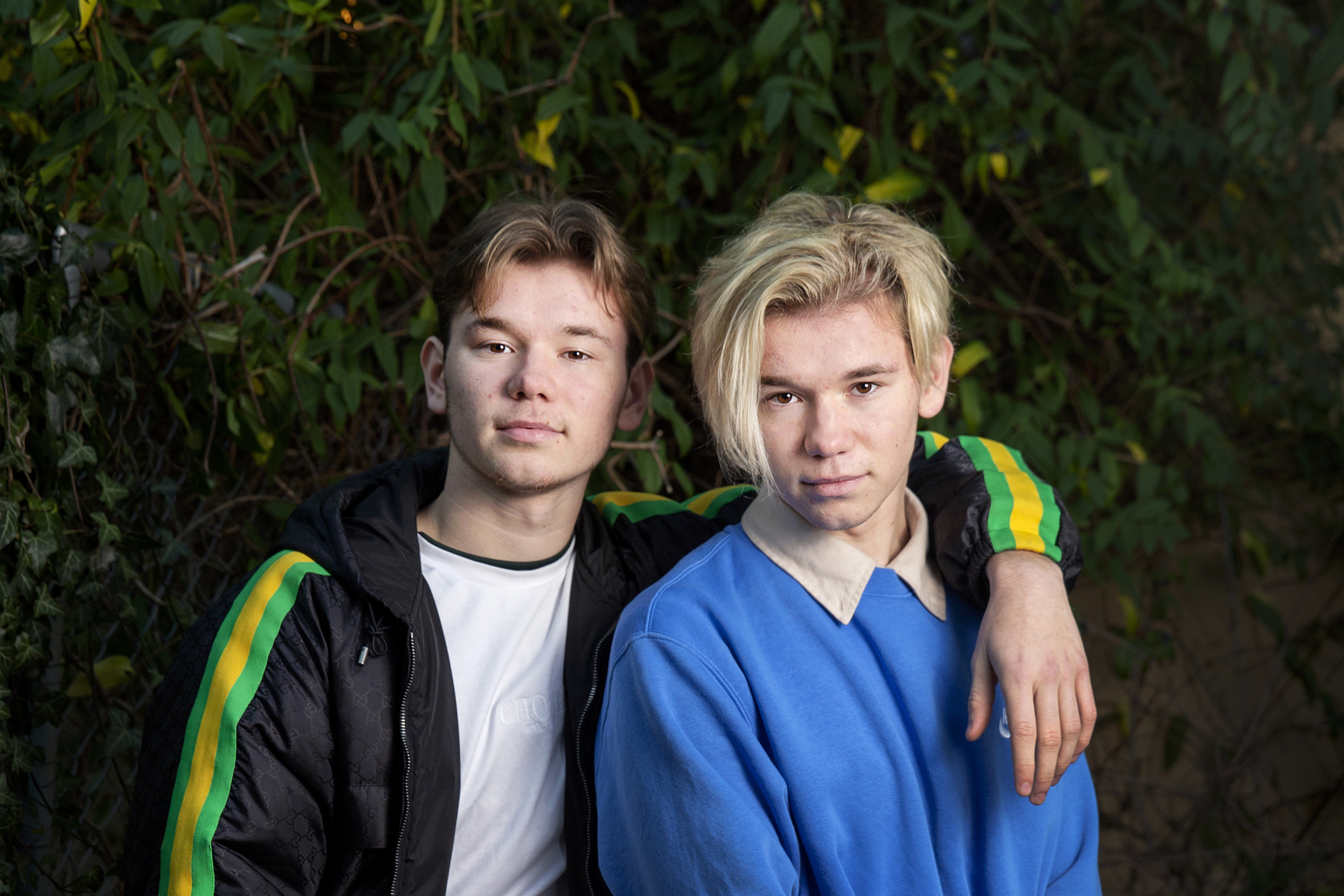Bilde av tvillingene og artistene Marcus og Martinus foran en murvegg utendørs.