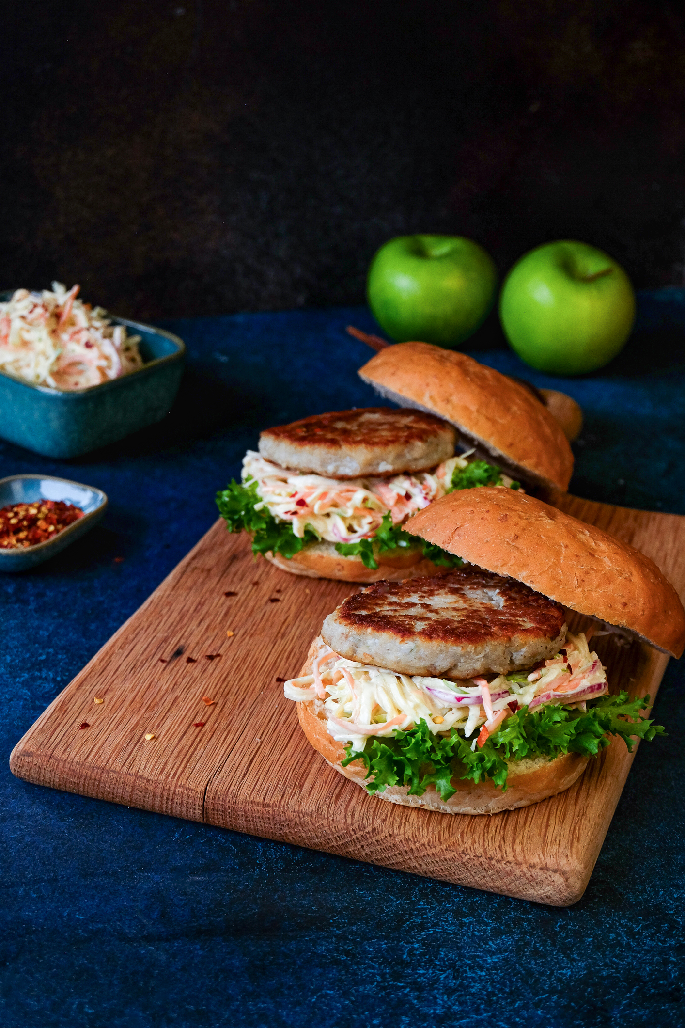 Foto: To burgere med grønn salat og coleslaw ligger klare på et skjærebrett.