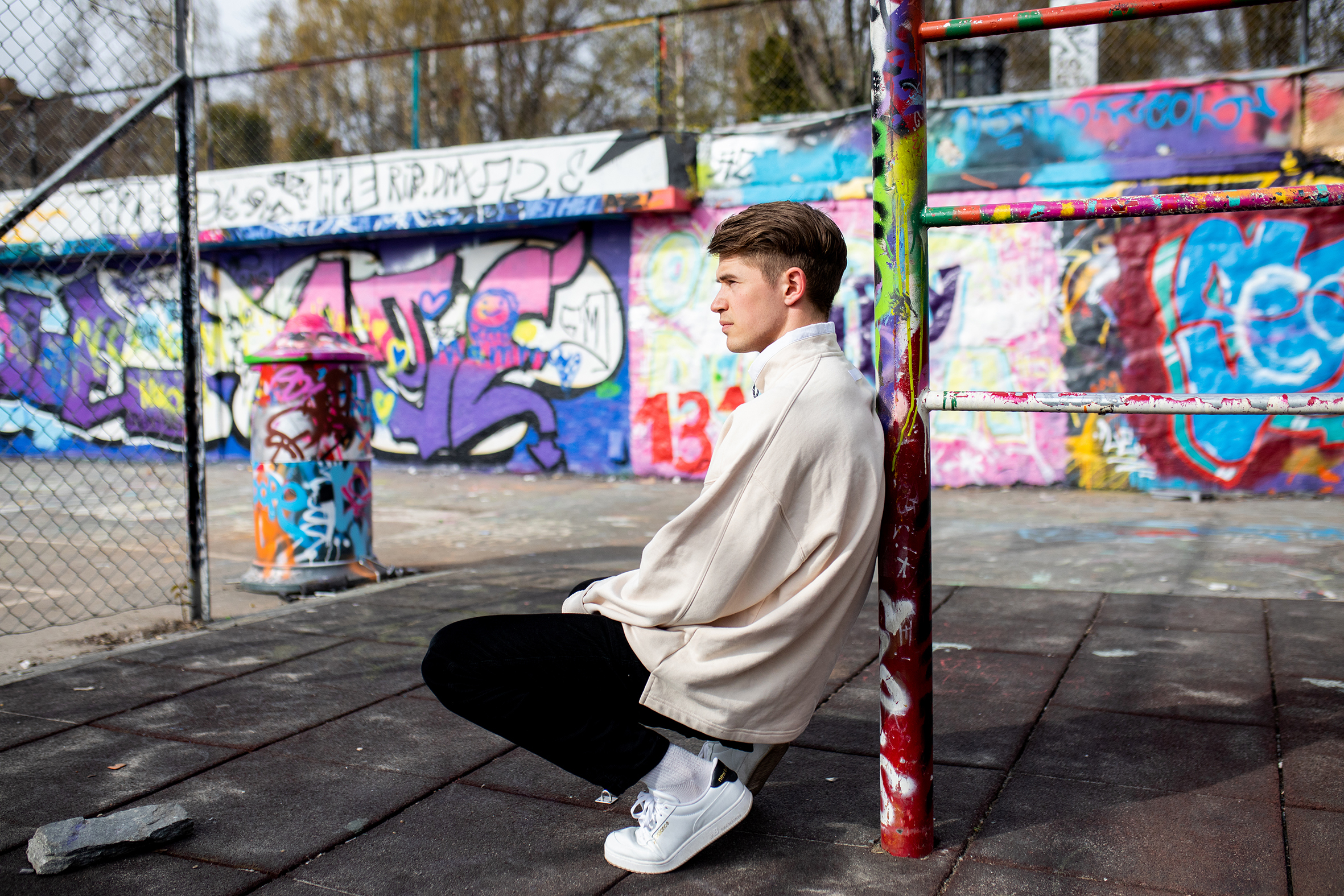 Martin sitter foran en vegg full av fargerik grafitti